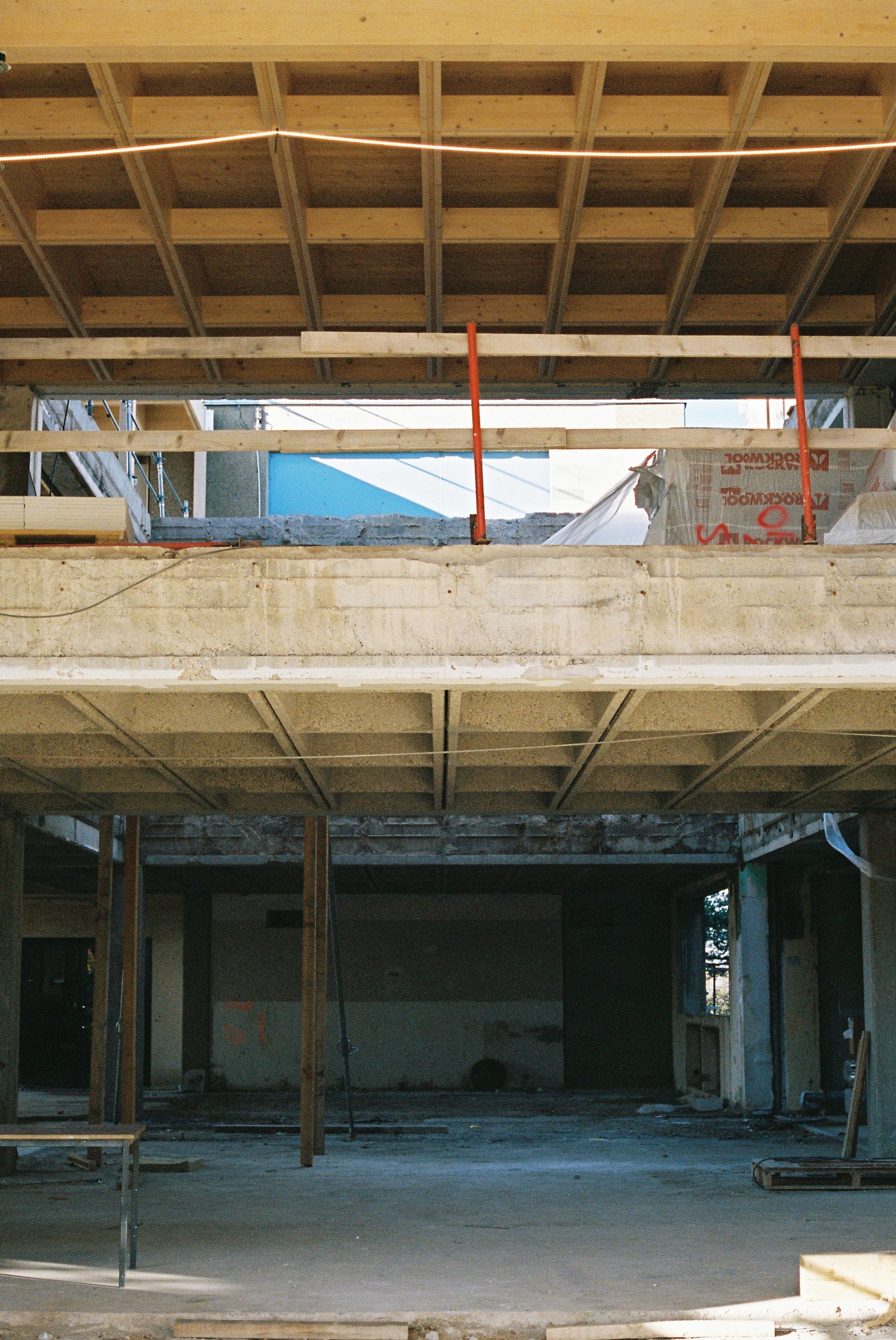 Vue intérieure du chantier de restructuration du collège Maryse Bastié à Dole, montrant la coexistence d’un plancher béton existant et d’une nouvelle structure bois.