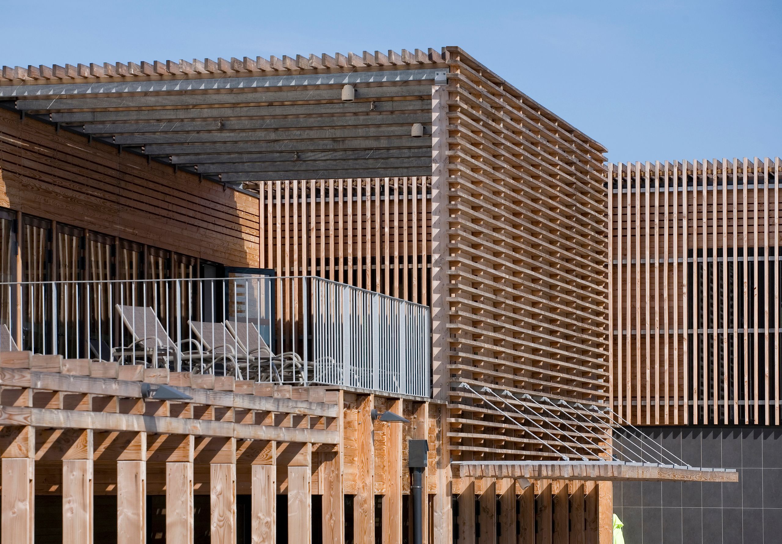 Centre thermal de Balaruc-les-Bains : façades en bois tissé, brise-soleil horizontaux et terrasse extérieure couverte, exprimant une volumétrie basse et linéaire.