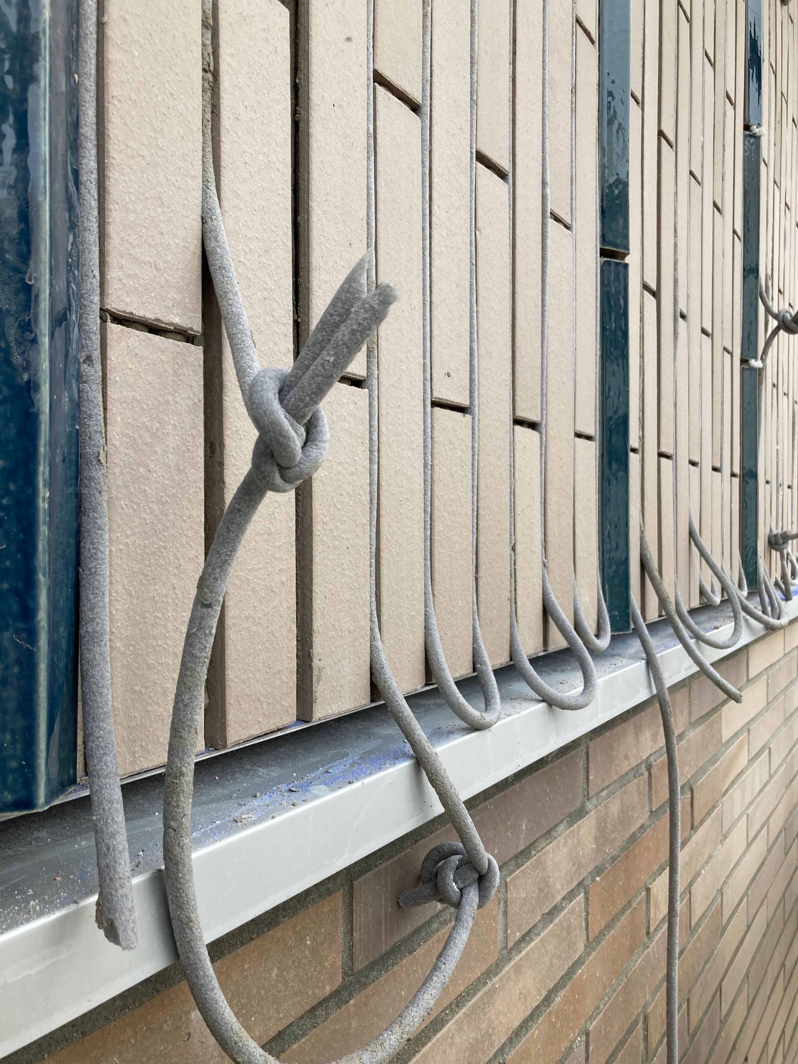 Détail de façade des groupes scolaires Jacqueline Auriol et Jean Jaurès au Bourget : briques, carreaux émaillés verticaux et garde-corps en acier noué.