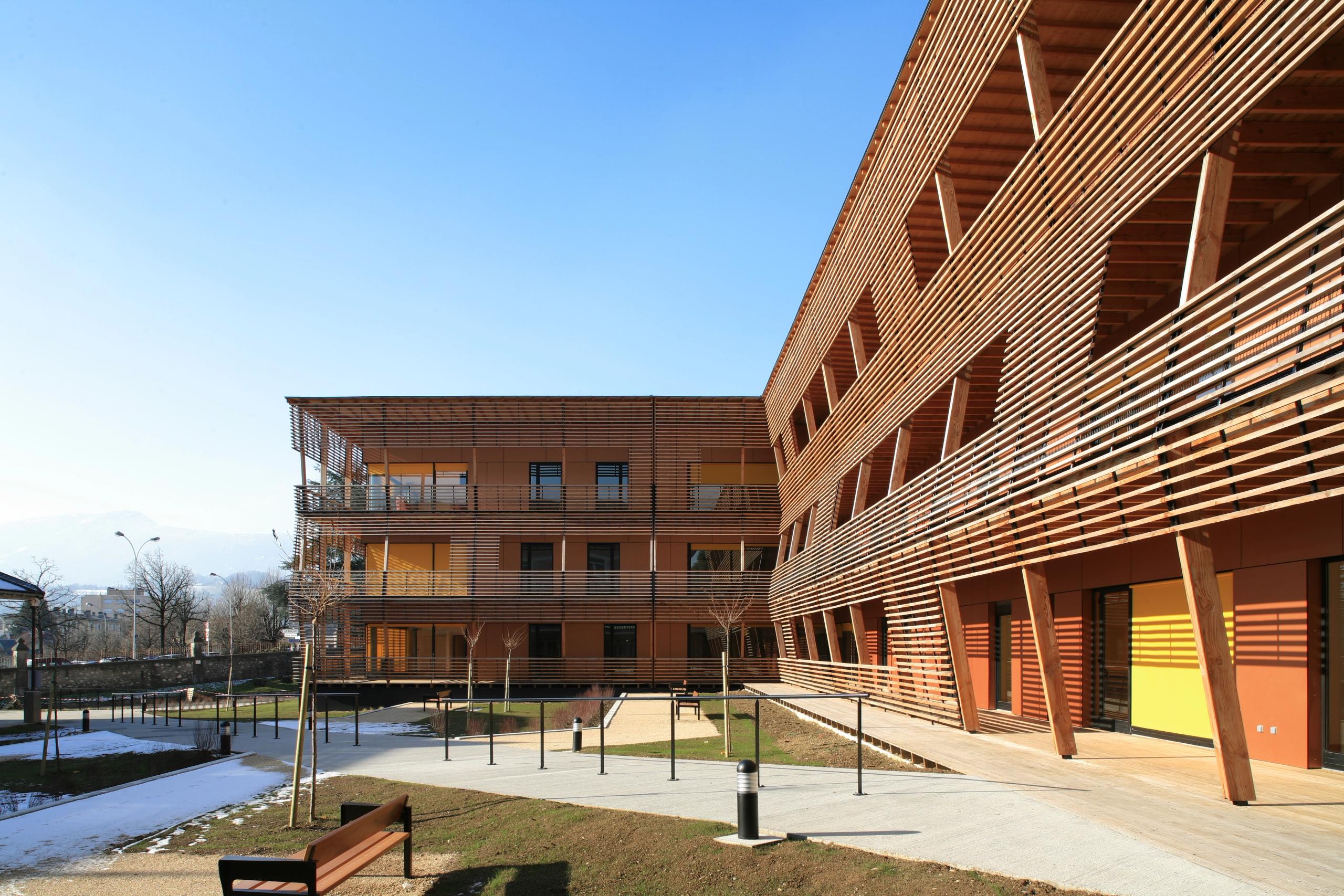 Extension de l’EHPAD de Chambéry par Tectoniques, bâtiment en T à façades bois à claire-voie, grandes terrasses et patios ouverts sur les jardins.