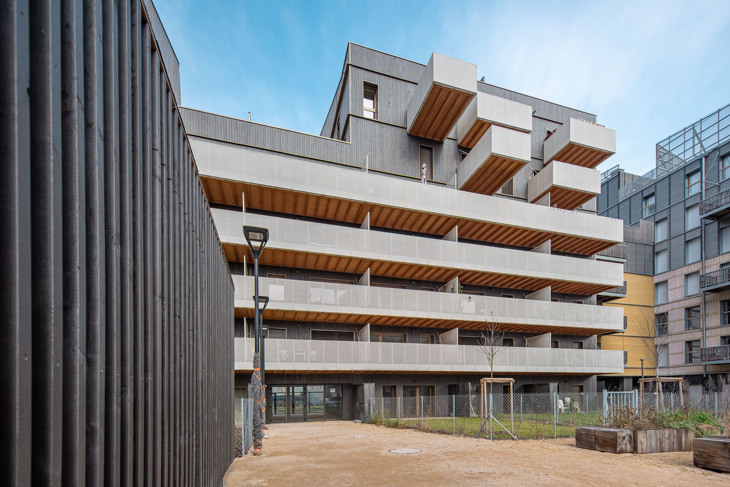 Vue de livraison des 98 logements Tectoniques à Strasbourg, façades bois-béton, balcons filants et volumes saillants organisant les loggias sur cour.