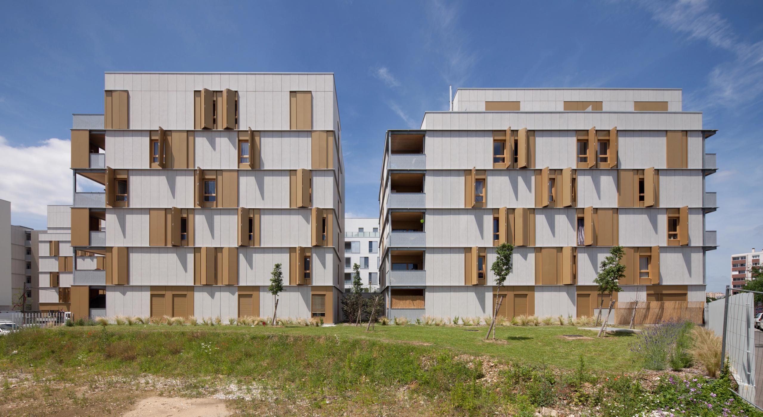 Vue de livraison des 55 logements Tectoniques à Lyon : deux volumes fins en béton et ossature bois, façades rythmées de volets métalliques et loggias traversantes.