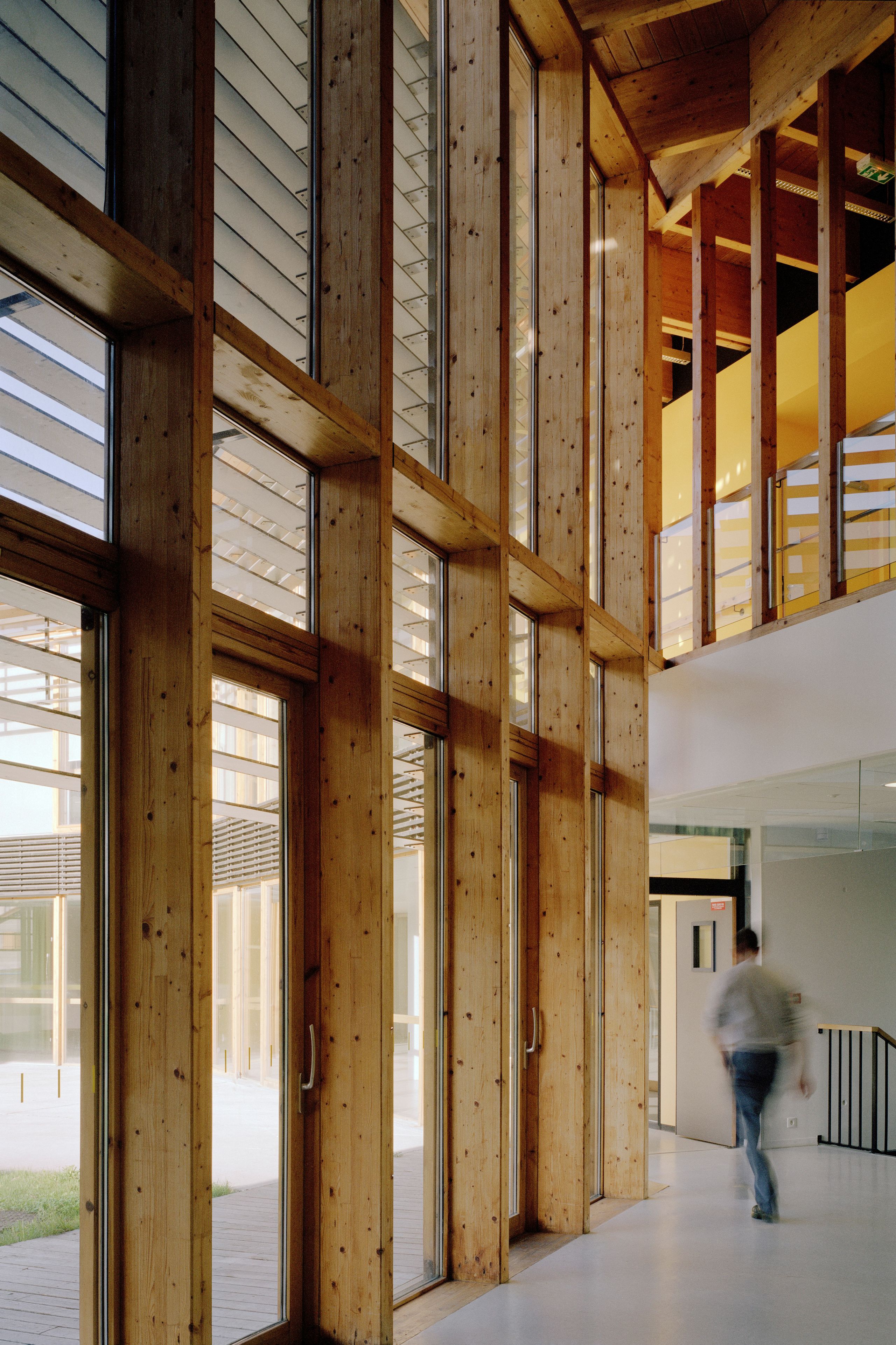 Galerie intérieure de l’EHPAD à Grenoble par Tectoniques, façade vitrée à ossature bois, brise-soleil orientables et vues sur le jardin central.