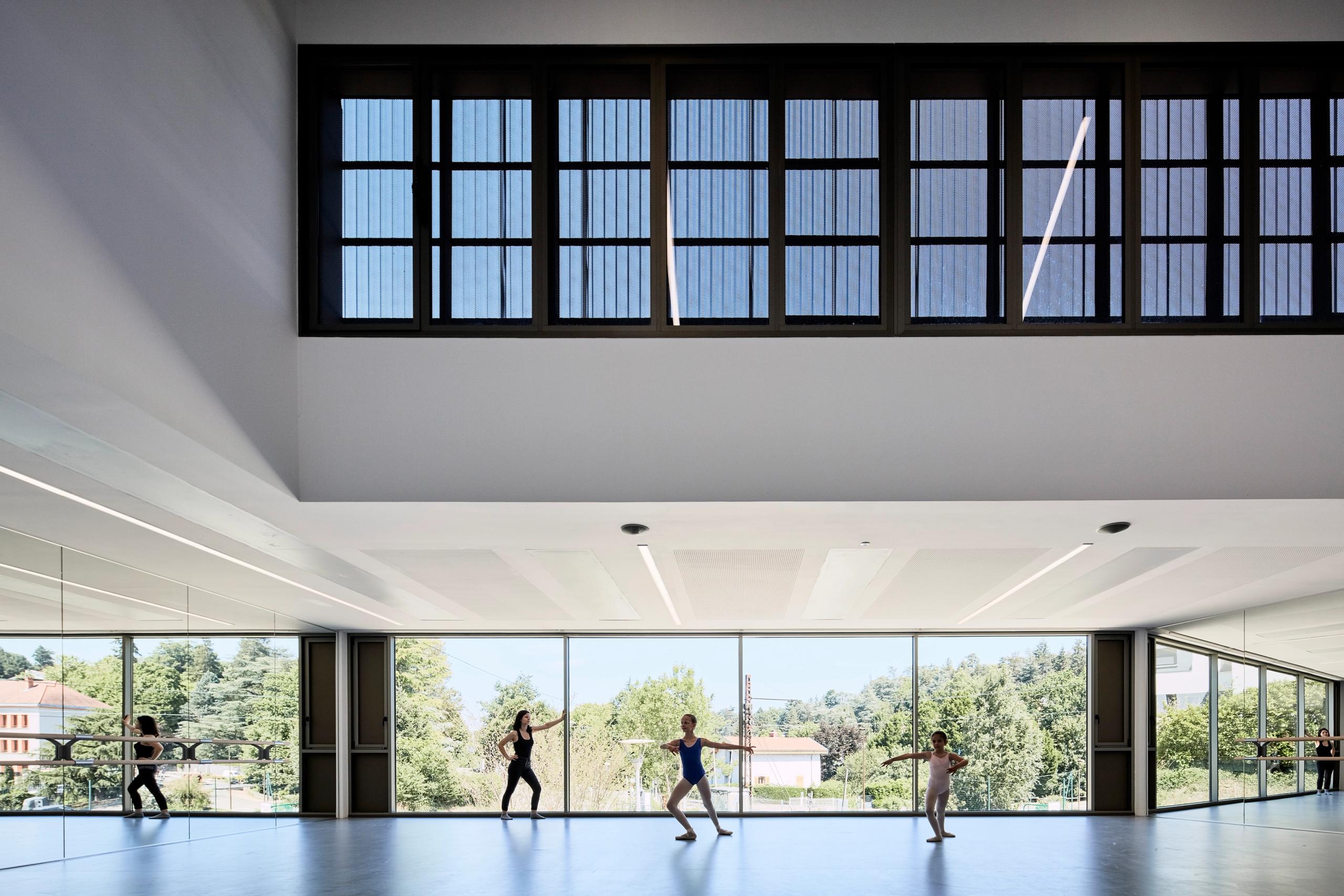 Salle de danse de la Maison des arts à Charbonnières-les-Bains, espace traversant vitré sur le paysage, plafond technique et bandeau vitré haut en façade.