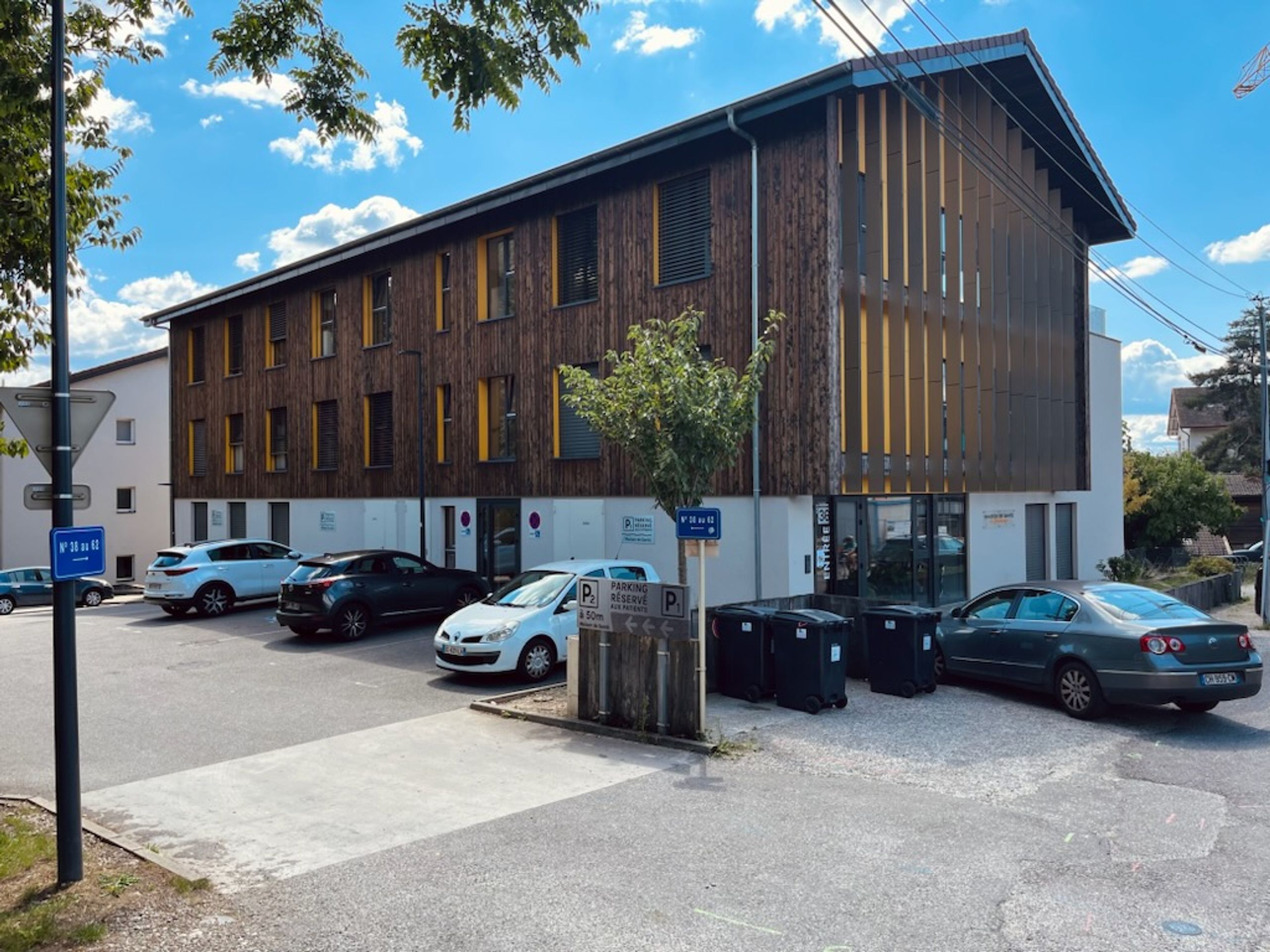 Maison de santé à Annecy par Tectoniques, volume compact en bois et enduit blanc, façades rythmées de lames verticales, large vitrage sur le rez-de-chaussée.