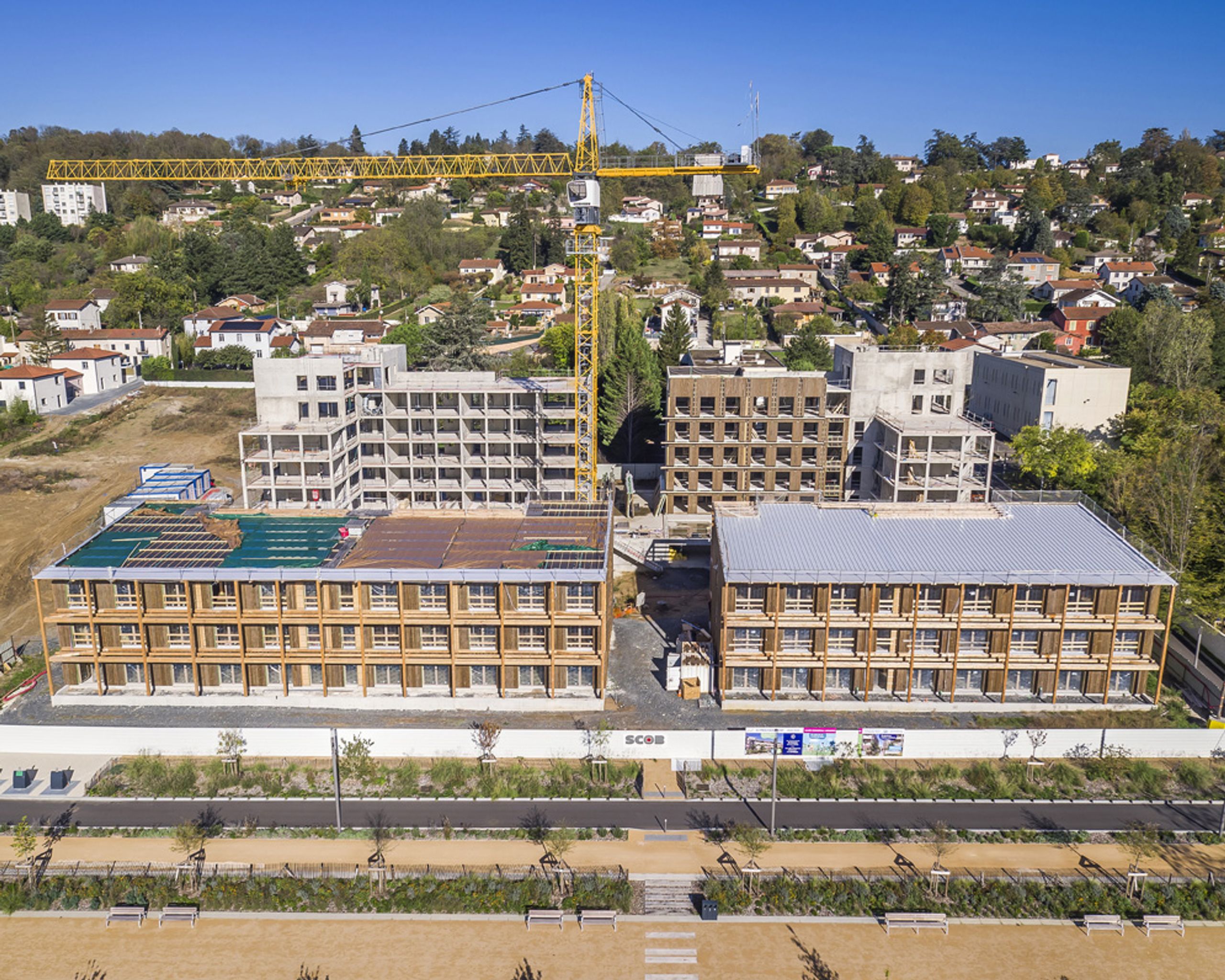 Vue aérienne du chantier des 84 logements à Trévoux par Tectoniques, volumes en gradins béton-bois, façades à ossature bois et exo-structures sous grue.