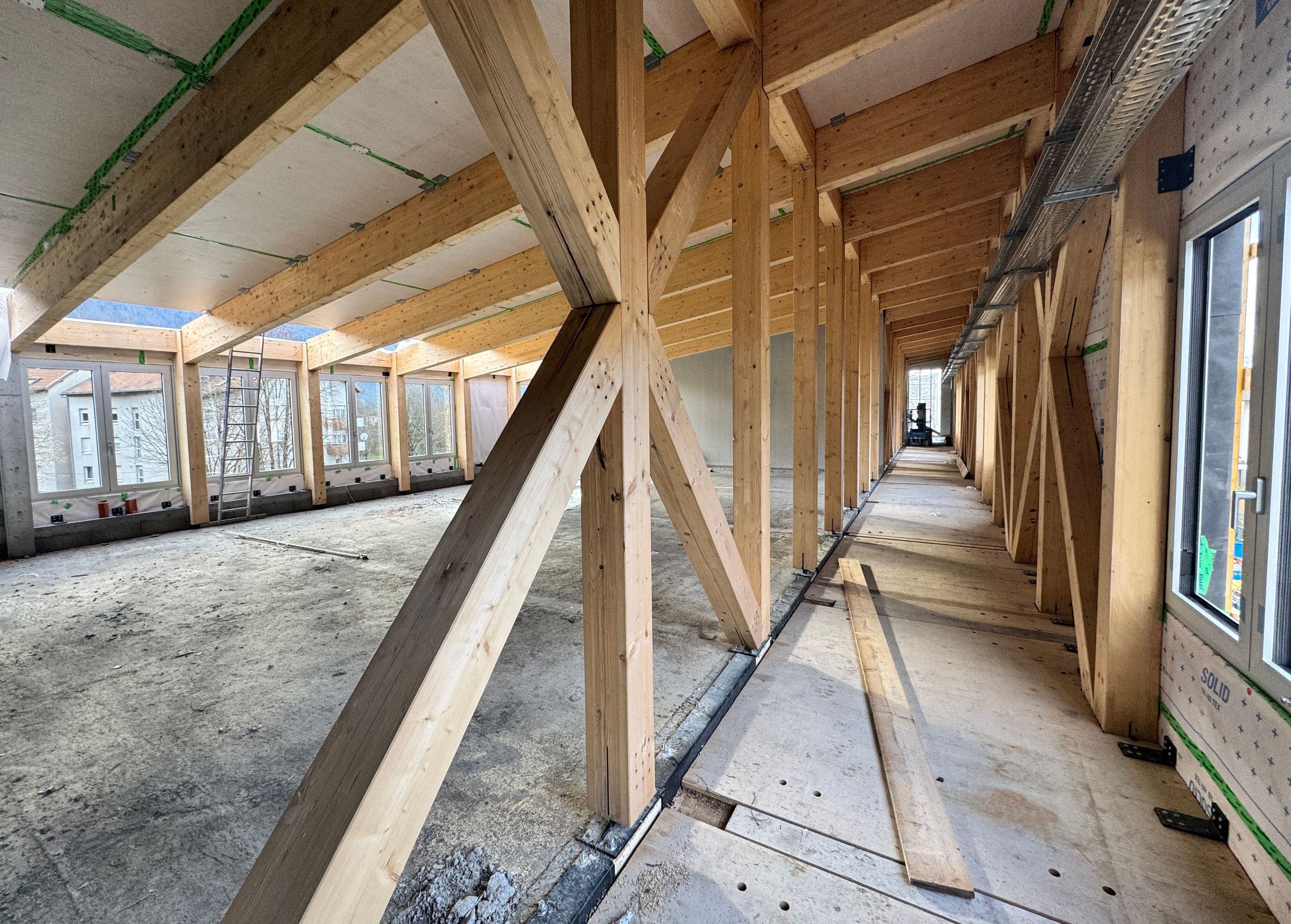 Structure bois en cours de chantier du School complex du Bouchet à Bonneville, montrant la surélévation-extension, la trame porteuse et les larges baies vitrées.