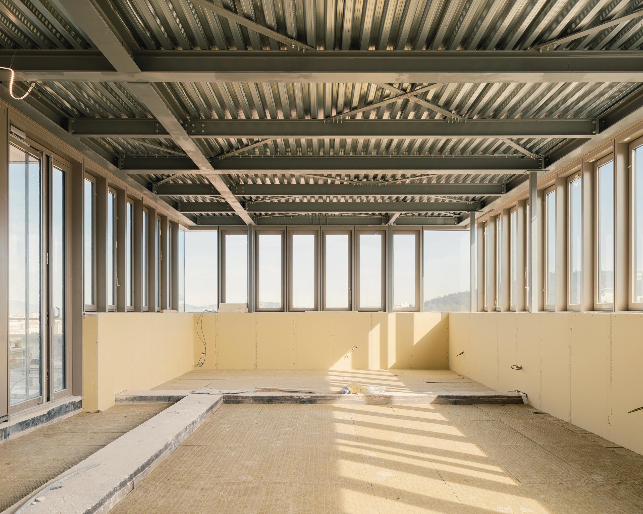 Plateau en chantier de l’IGH Émile Loubet à Saint-Étienne, niveau attique vitré sur trois côtés, structure métallique apparente et parois isolées en cours de finition.