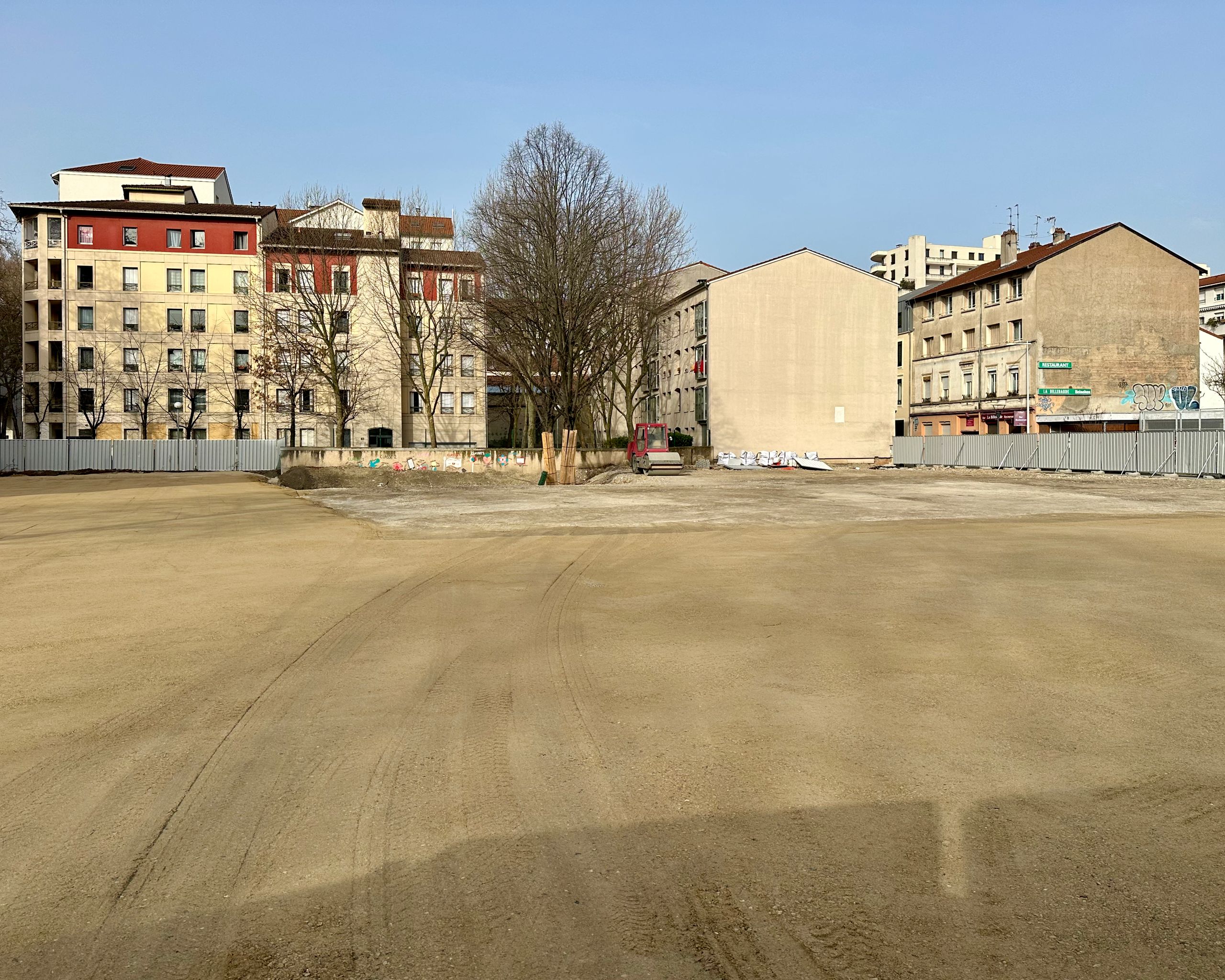 Cleared urban plot in Lyon for the Pompidou Mourguet School complex, with graded ground, site fencing and surrounding masonry housing blocks.