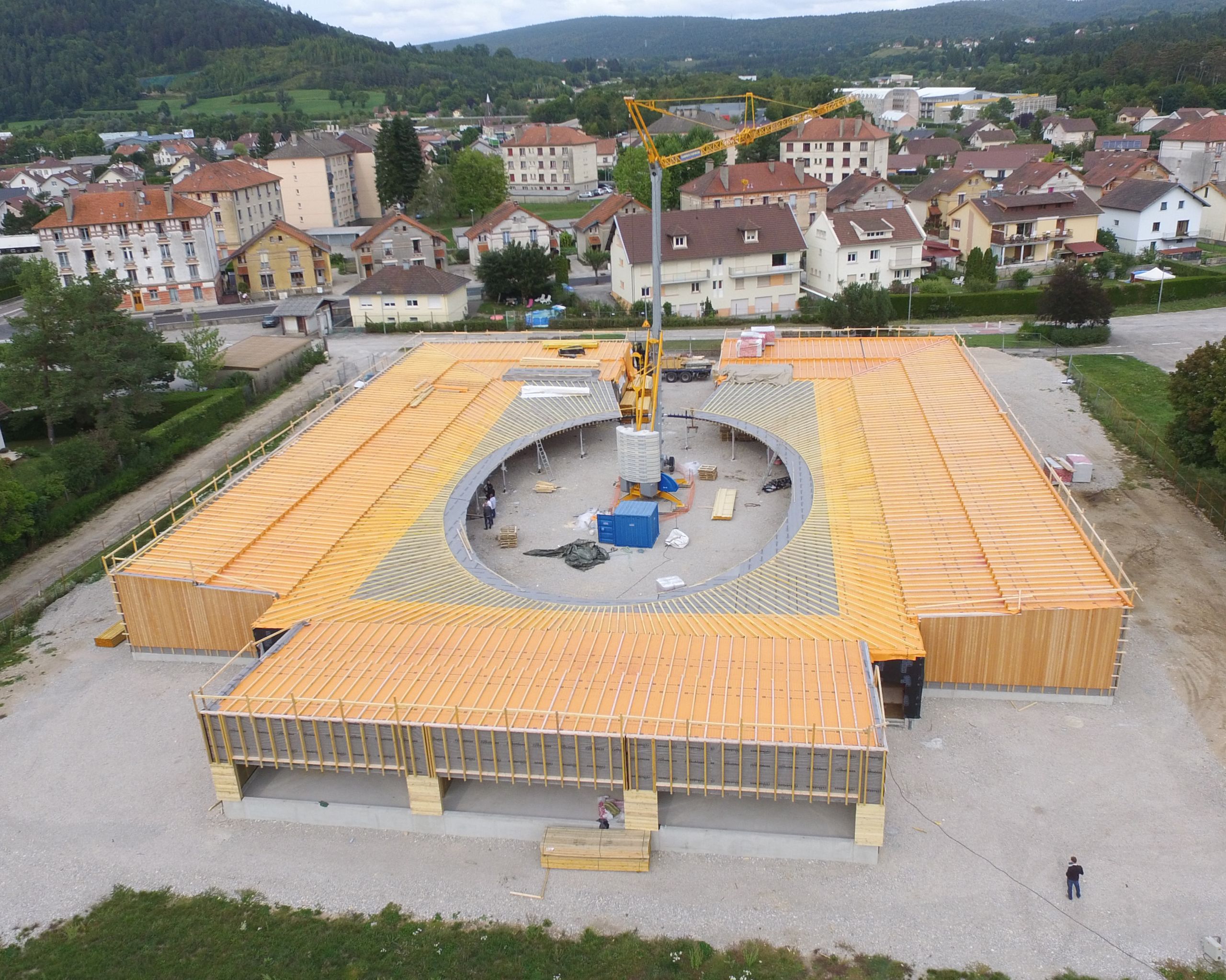 Vue aérienne du chantier de l’école élémentaire Hubert Reeves à Champagnole, bâtiment en ossature bois organisé autour d’une cour elliptique centrale.