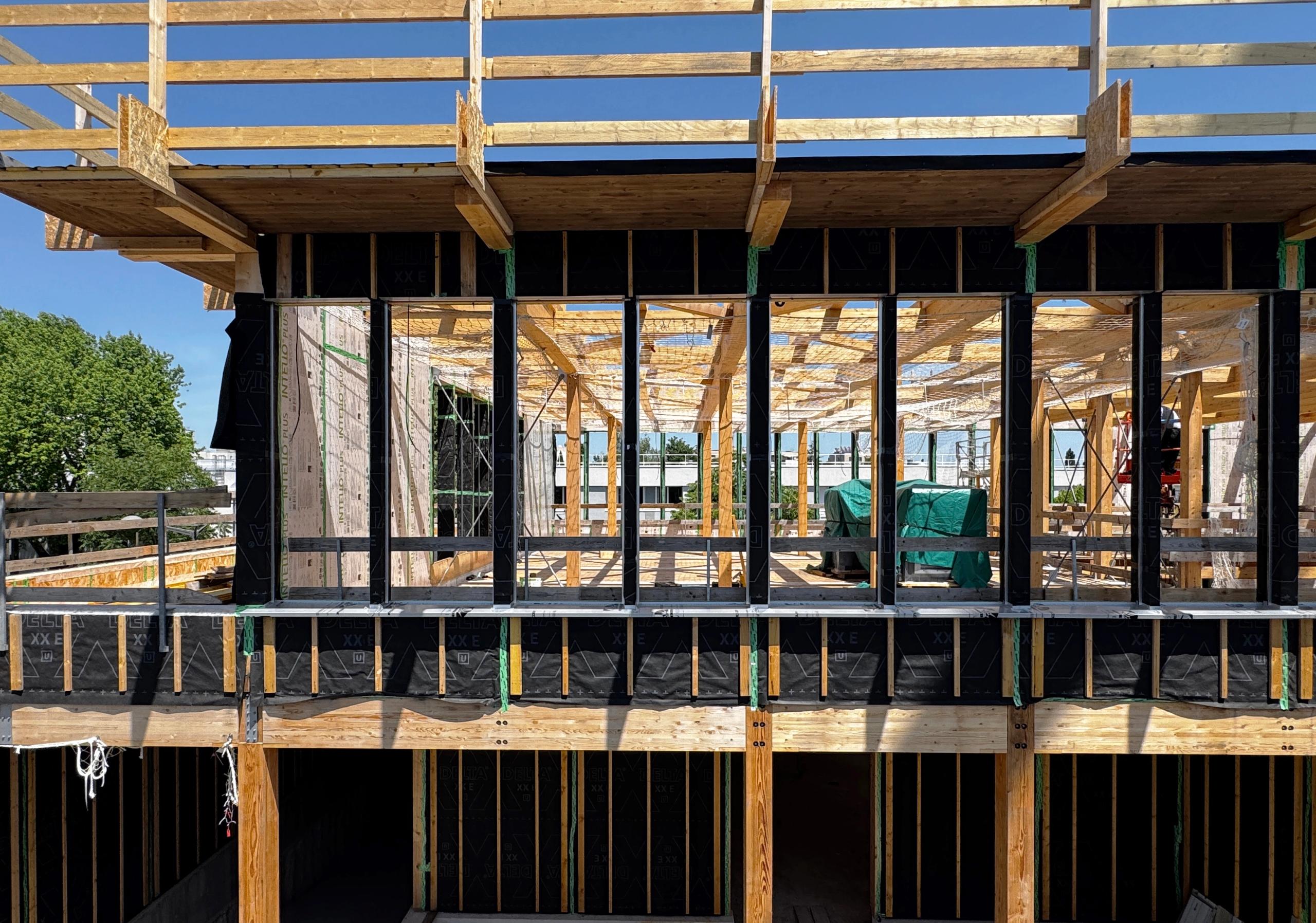 Chantier de la Cité campus Assia Djebar à Vaulx-en-Velin : structure bois apparente, trame régulière de poteaux et poutres tissées, volumes ouverts sur la ville.