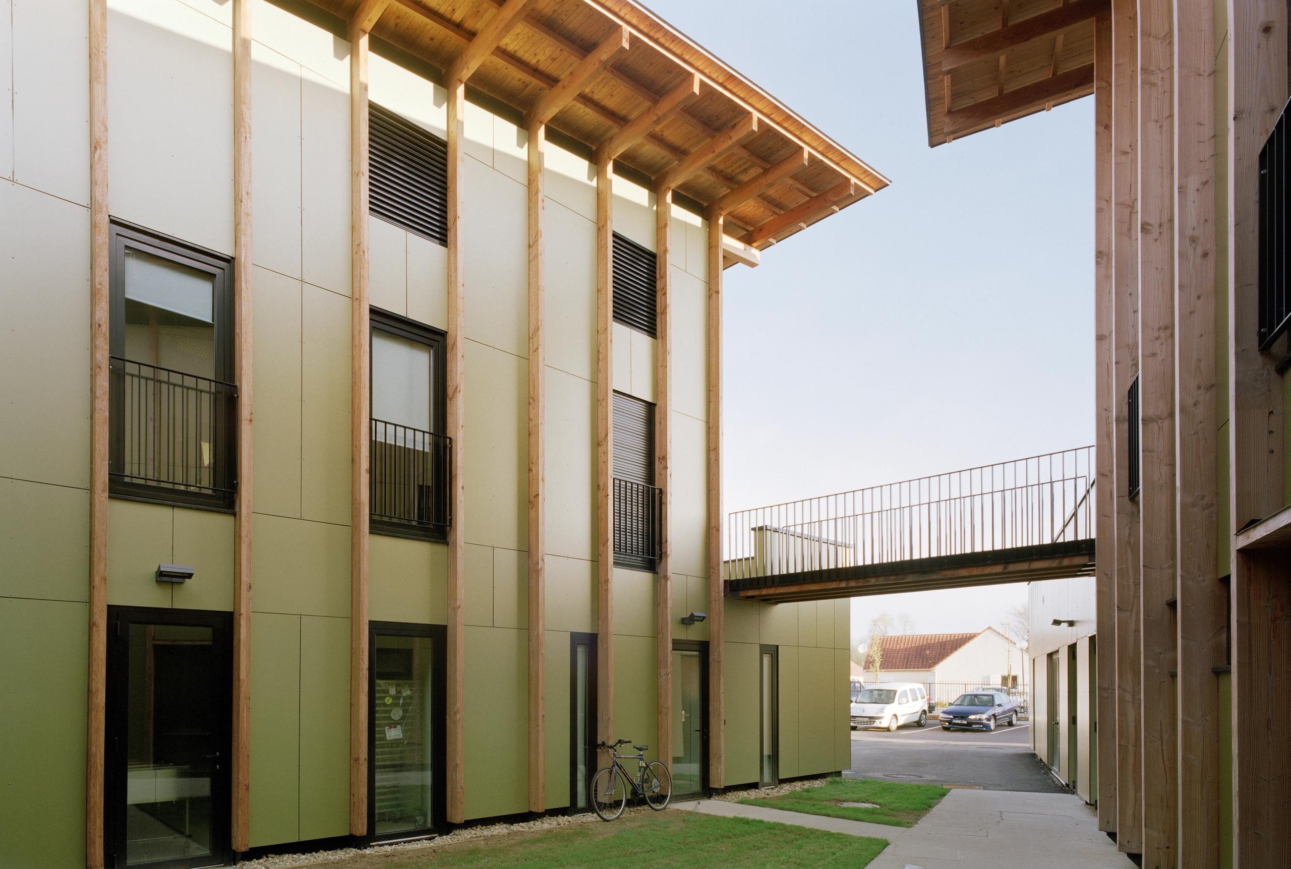 Cour de l’EHPAD de Mervans par Tectoniques, montrant façades bois et panneaux clairs, toiture débordante et passerelle reliant les deux ailes autour du jardin.