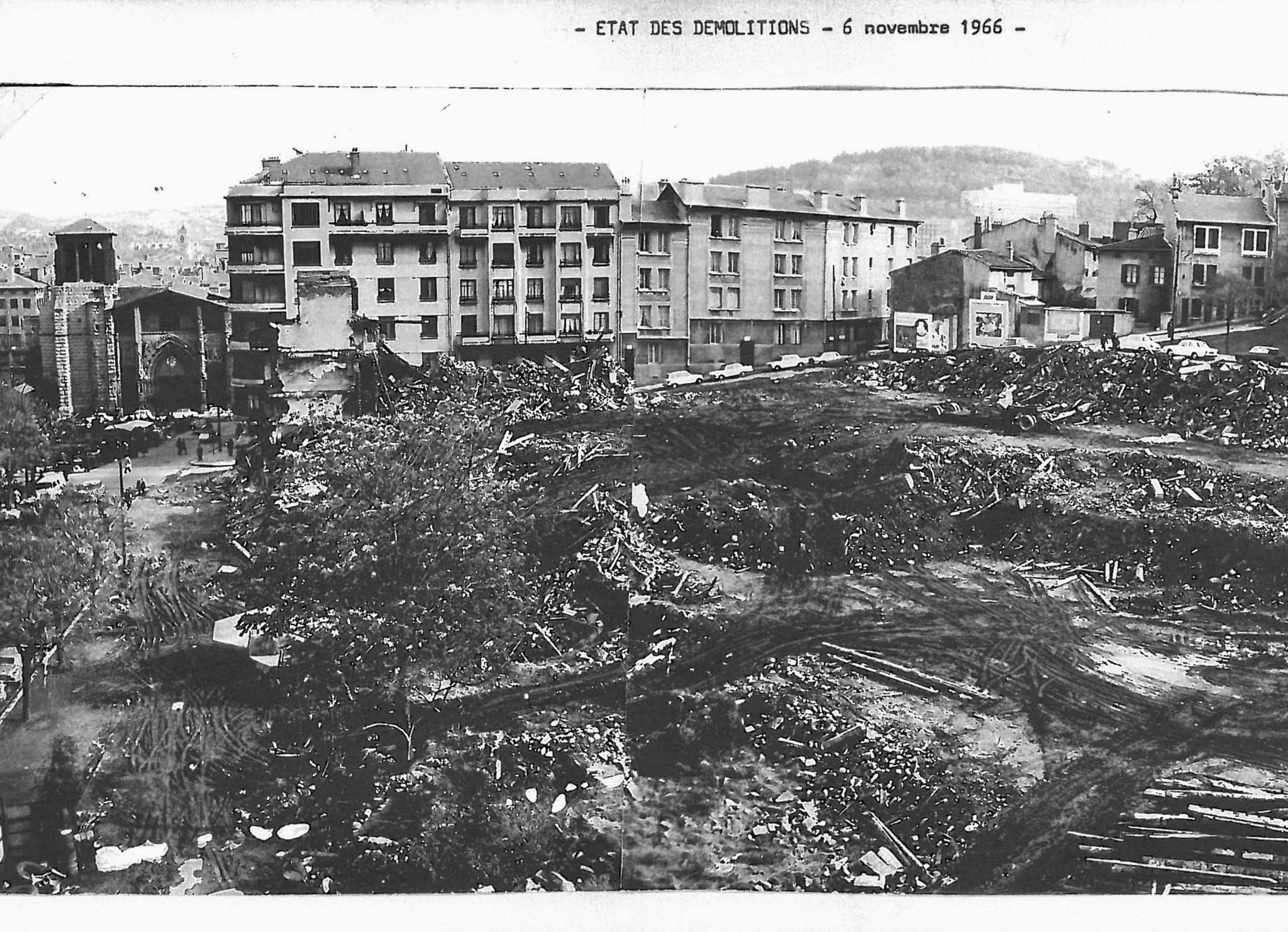Vue d’archives du site à Saint-Étienne en 1966 : vaste terrain en démolition au premier plan, bordé d’immeubles d’habitation et d’une église en arrière-plan.