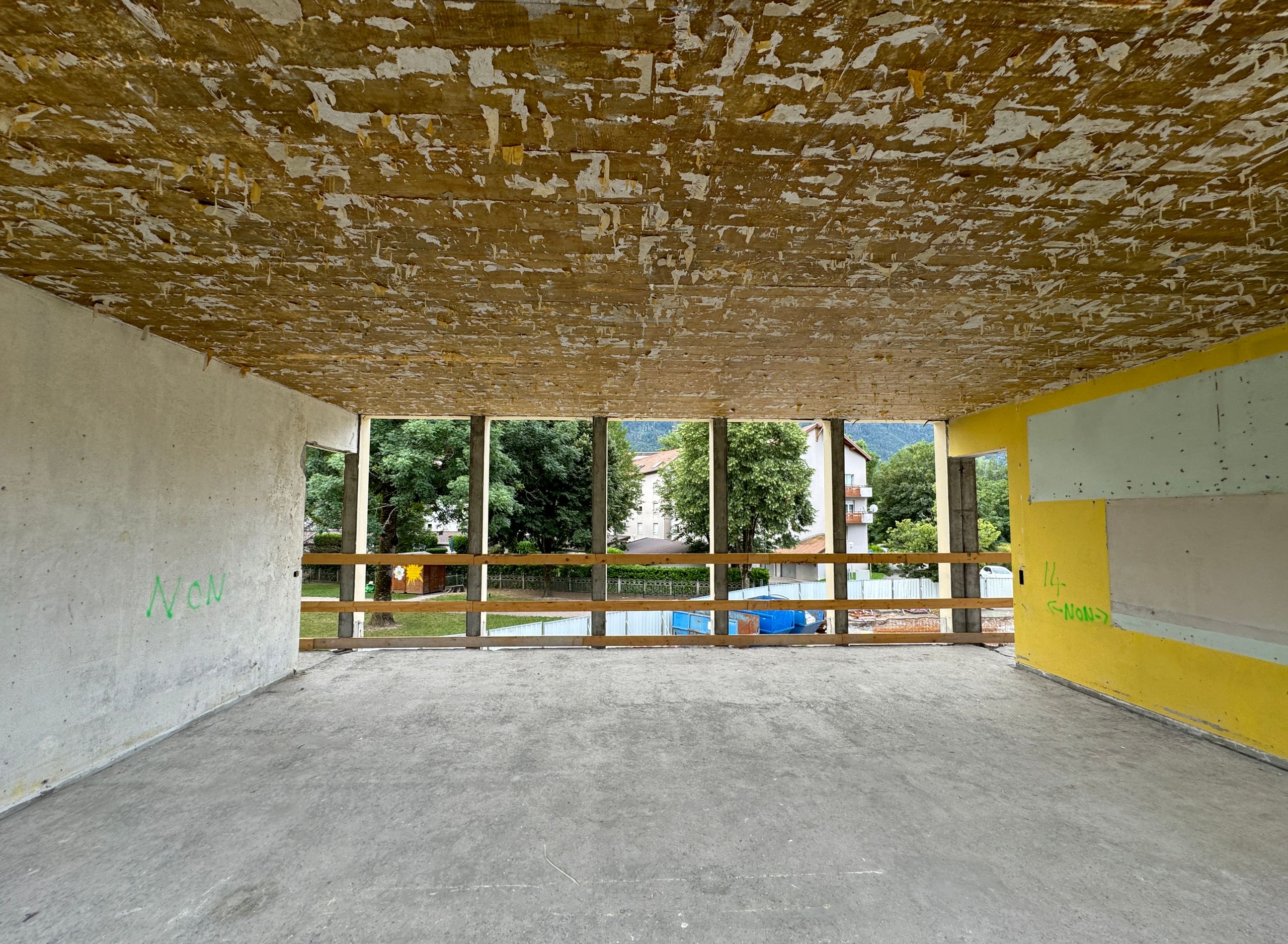 Phase de curage du groupe scolaire du Bouchet à Bonneville, plateau béton nu ouvert sur l’extérieur, structure poteaux-poutres apparente et façades déposées.