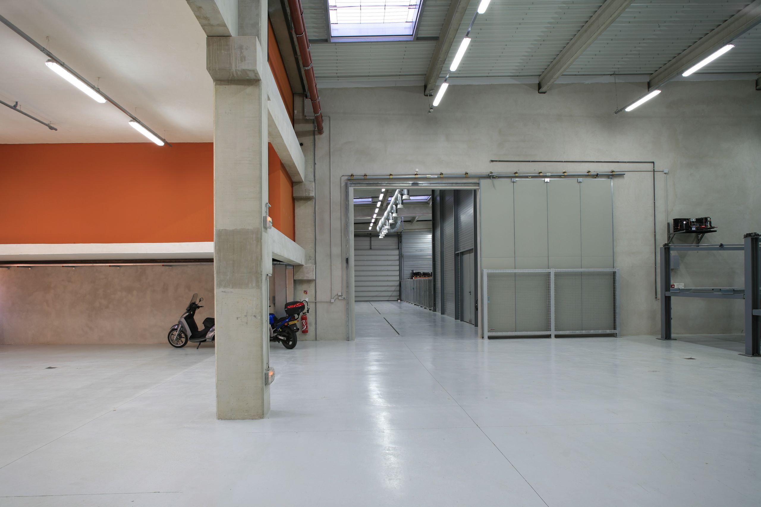Vue intérieure du Département des Recherches Subaquatiques et Sous-Marines à Marseille, grand hall technique en béton et métal, sols clairs, cloisons coulissantes et sheds vitrés.
