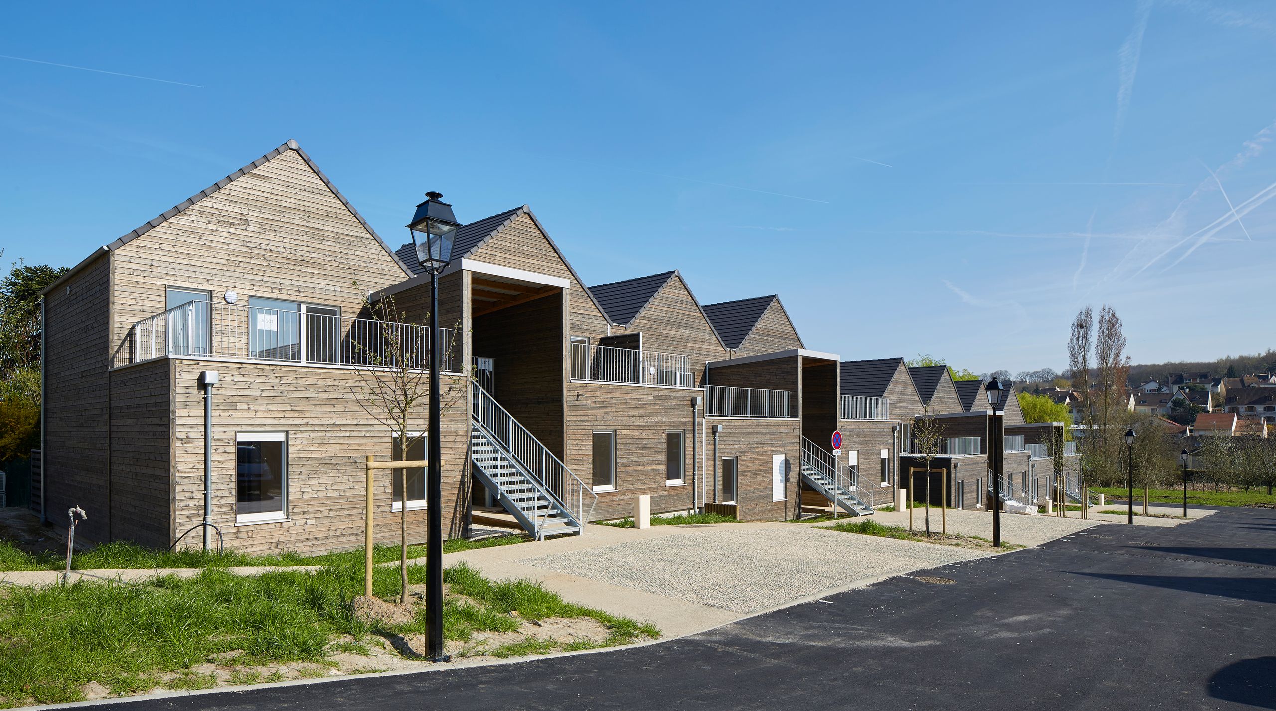 Vue du projet de 36 logements à Vauhallan par Tectoniques : volumes en bois à toitures à deux pans, escaliers extérieurs métalliques et cheminements paysagers.