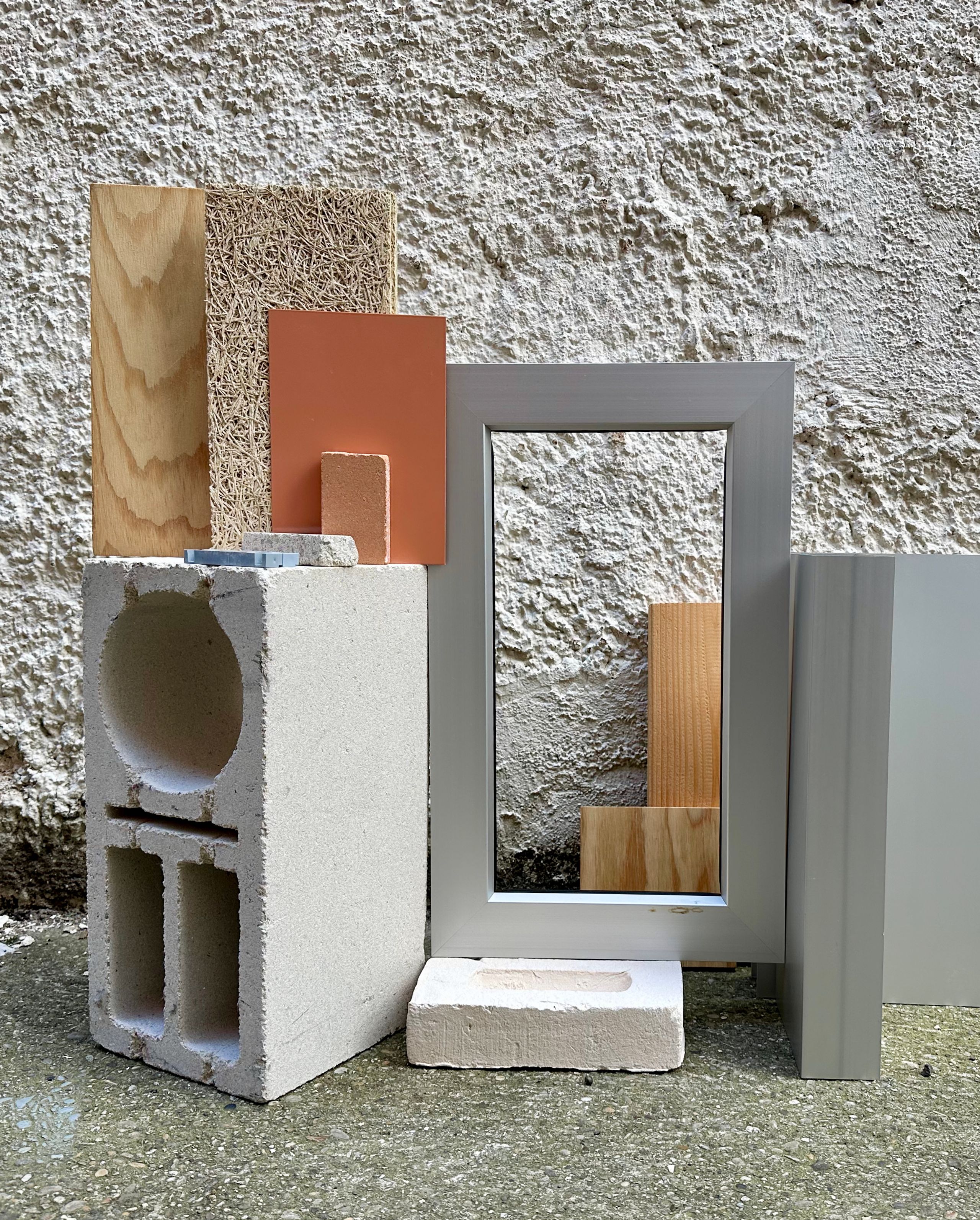 Material palette for the Pompidou Mourguet School Complex in Lyon, showing masonry block, timber samples and metal frame elements against a rough wall.