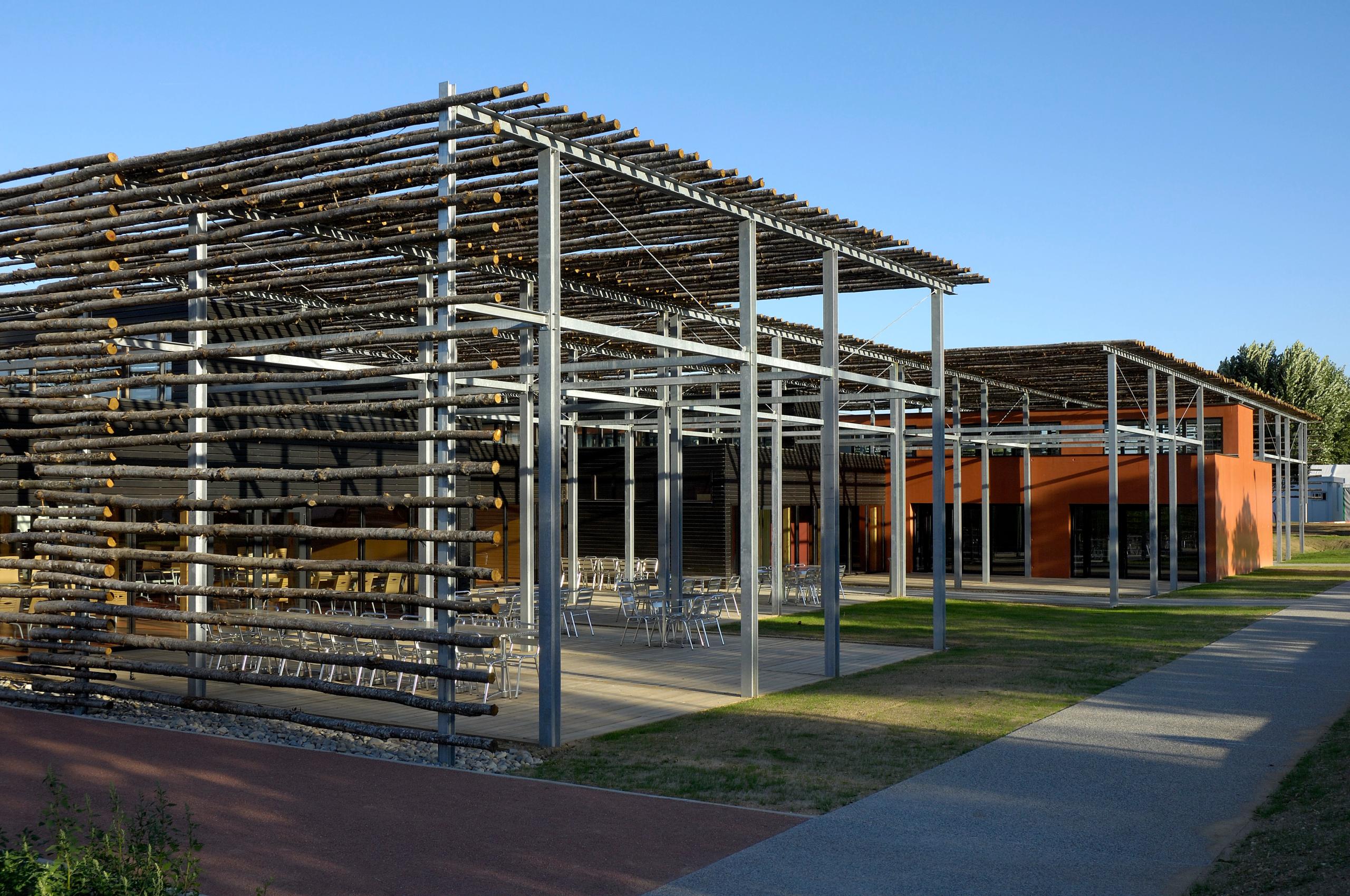 Restaurant administratif du CETE à Bron : volumes orangés sous exostructure métallique, ombrière en baliveaux de châtaignier et terrasses extérieures.