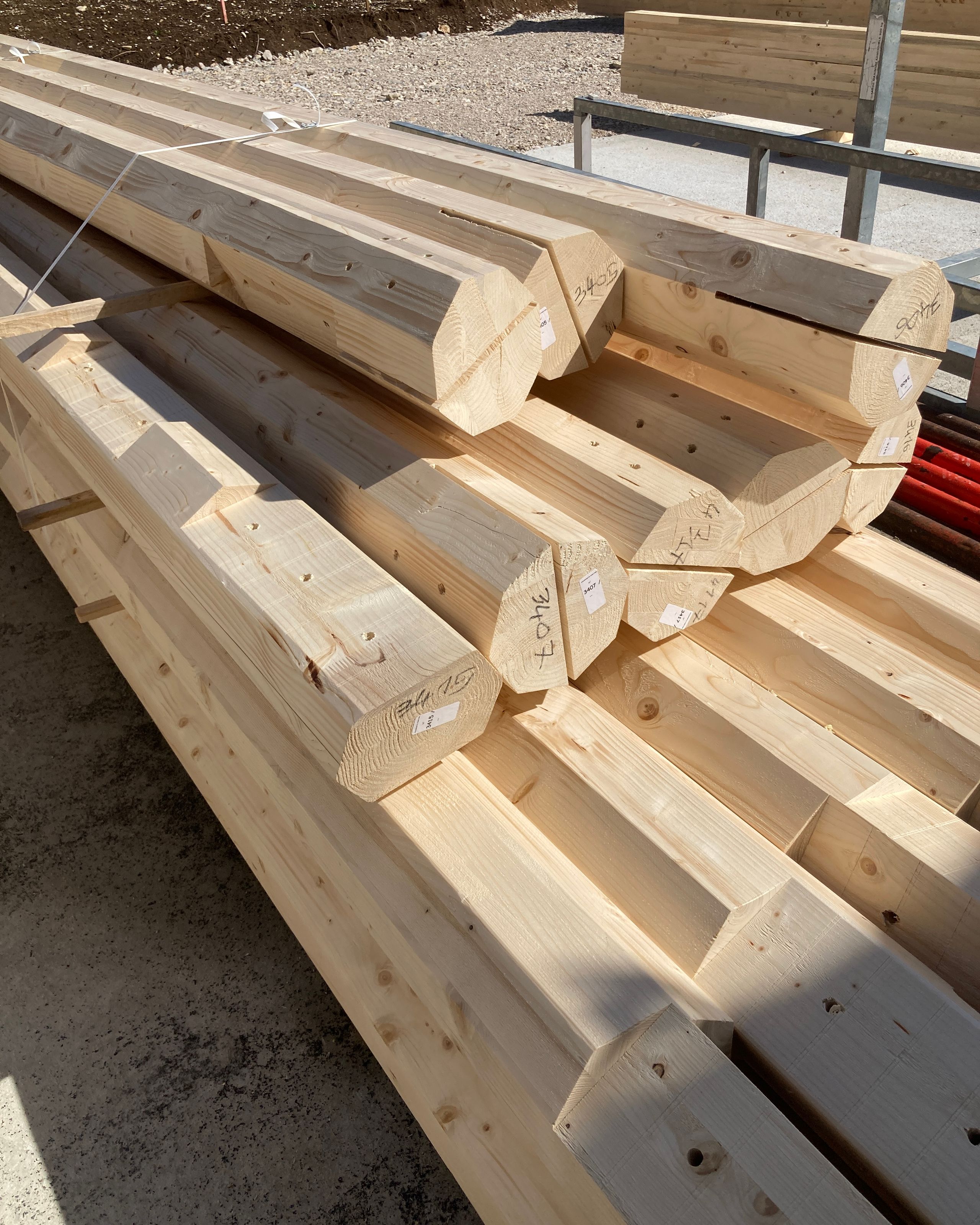 Chantier du groupe scolaire Louis Pergaud à Levier : empilement de poutres en bois local usinées, prêtes pour la structure porteuse du bâtiment.