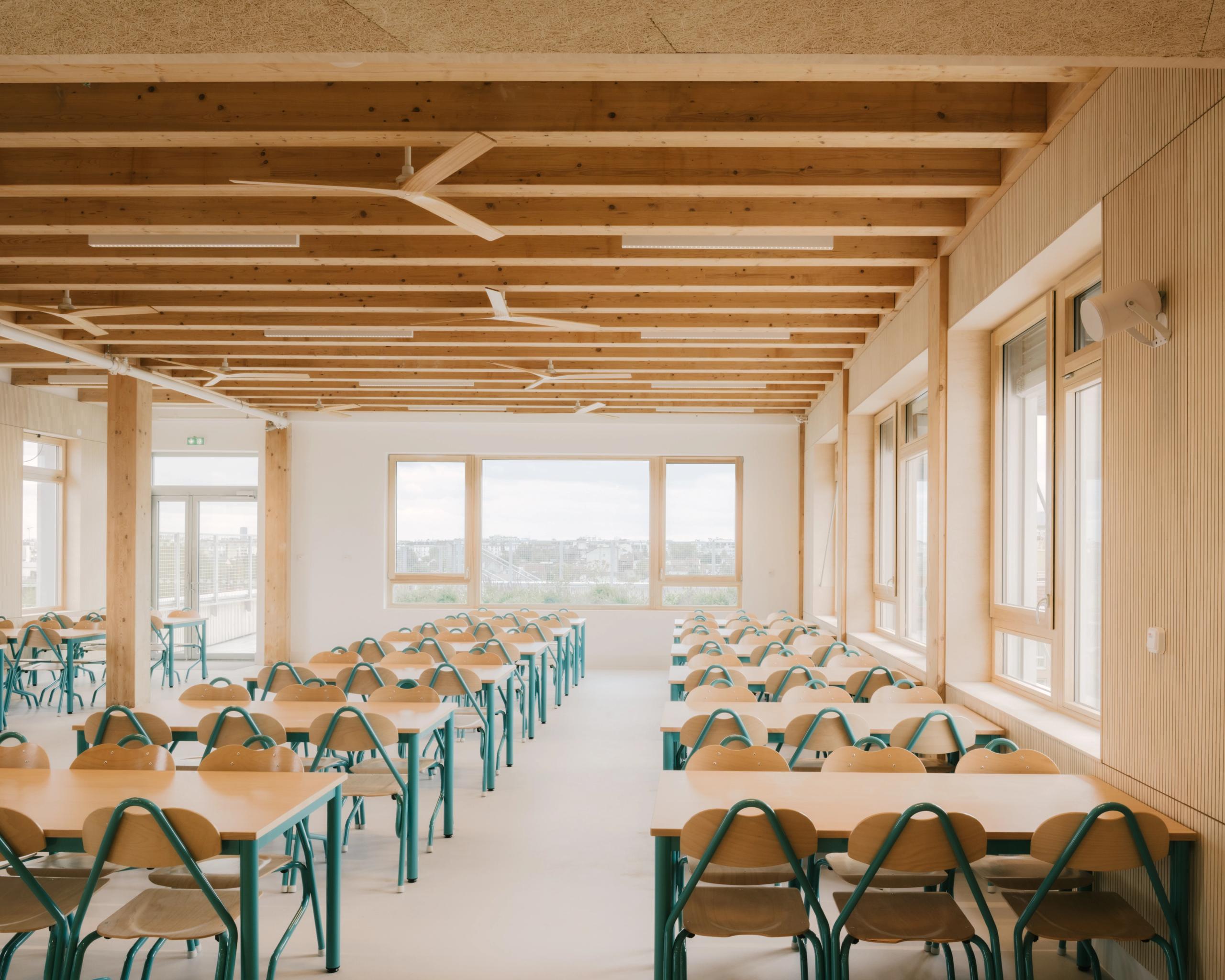 Cafeteria du Groupe scolaire Dominique Frelaut à Colombes, vaste plateau lumineux à structure bois apparente, baies vitrées et mobilier aligné.