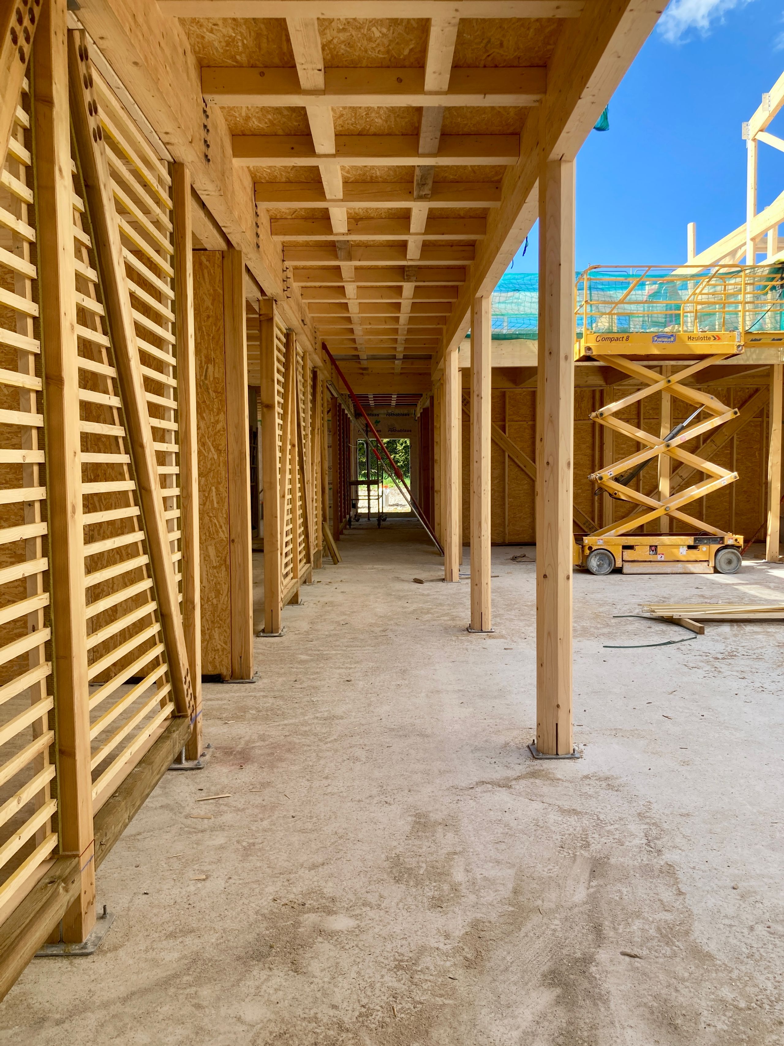 Chantier du groupe scolaire Louis Pergaud à Levier : galerie en structure bois apparente, lames verticales filtrantes et planchers en panneaux OSB.