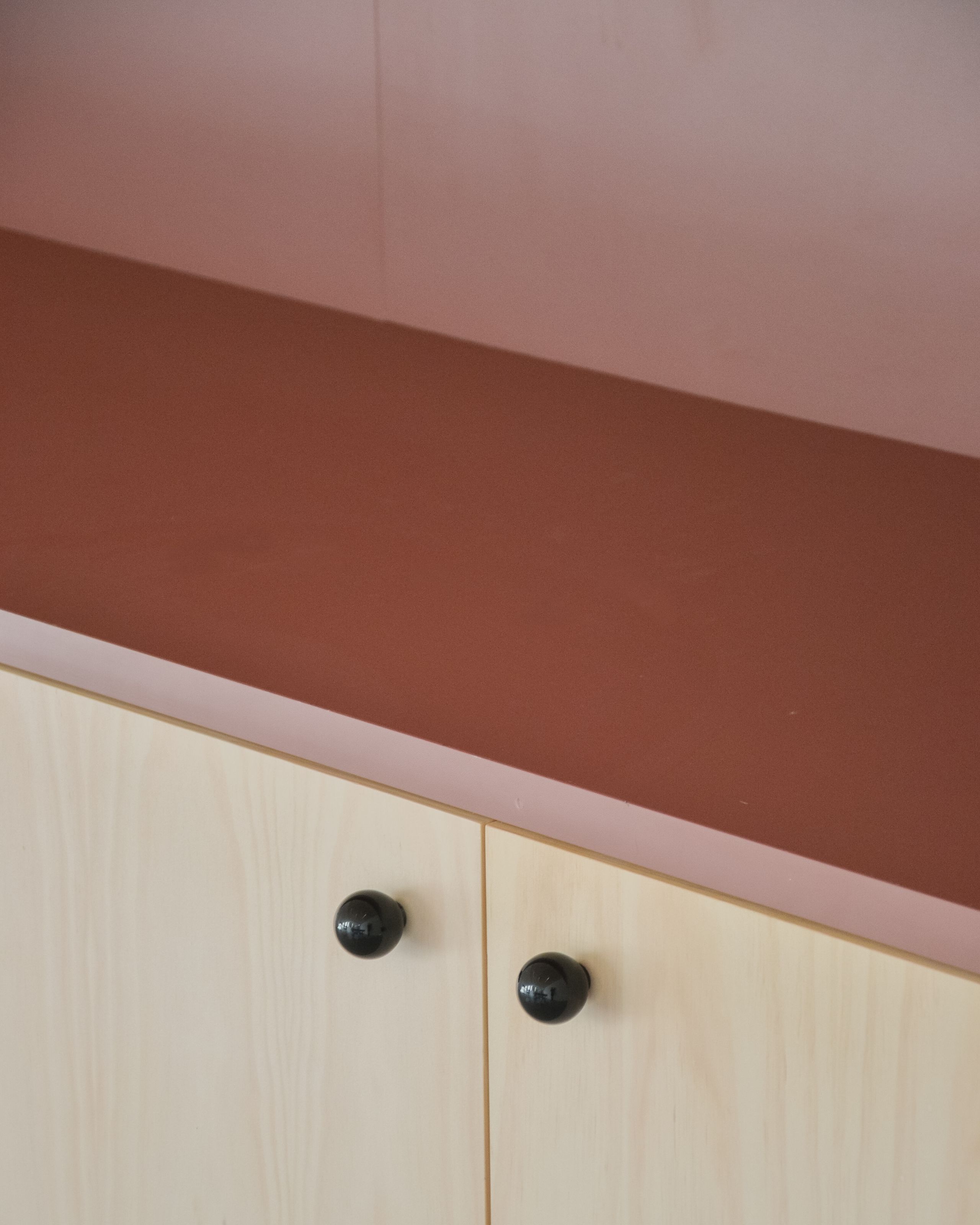 Détail intérieur du groupe scolaire du Bouchet à Bonneville : mobilier en contreplaqué clair, plan de travail ocre et crédence rose, traitement sobre des finitions.