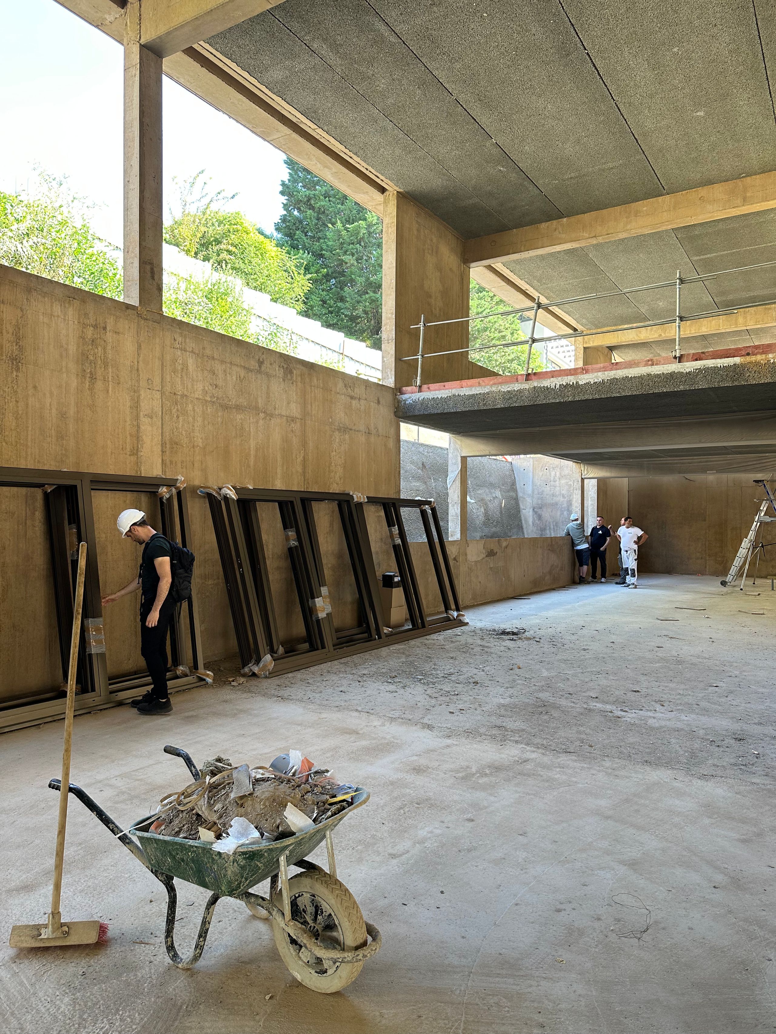 Chantier de la Maison des familles à Limonest : vaste plateau en béton teinté, double hauteur ouverte sur le paysage, circulations en cours de mise en œuvre.