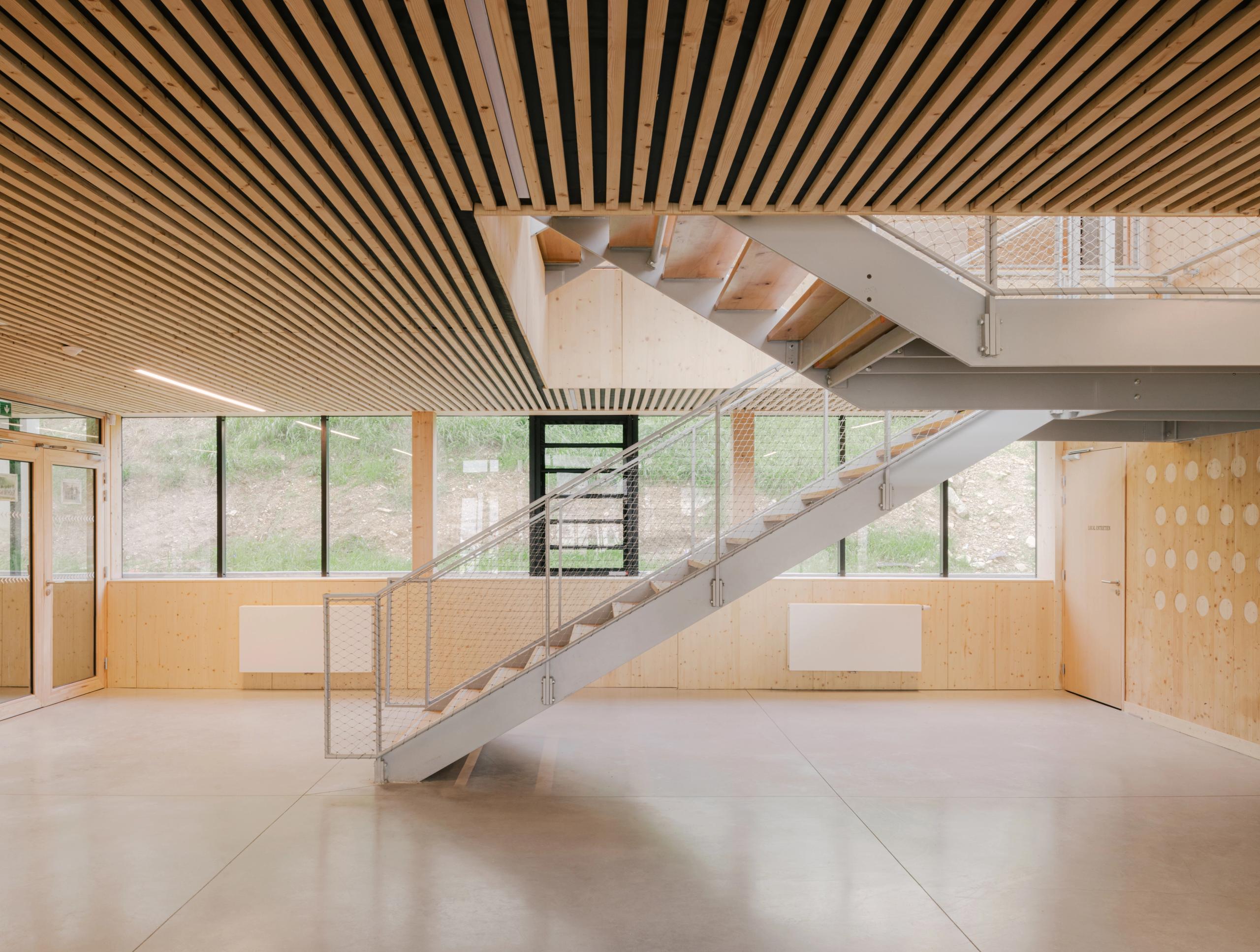 Hall intérieur de la médiathèque et School complex Claudie Haigneré aux Pennes-Mirabeau, escalier métallique, bois apparent et lumière naturelle traversante.