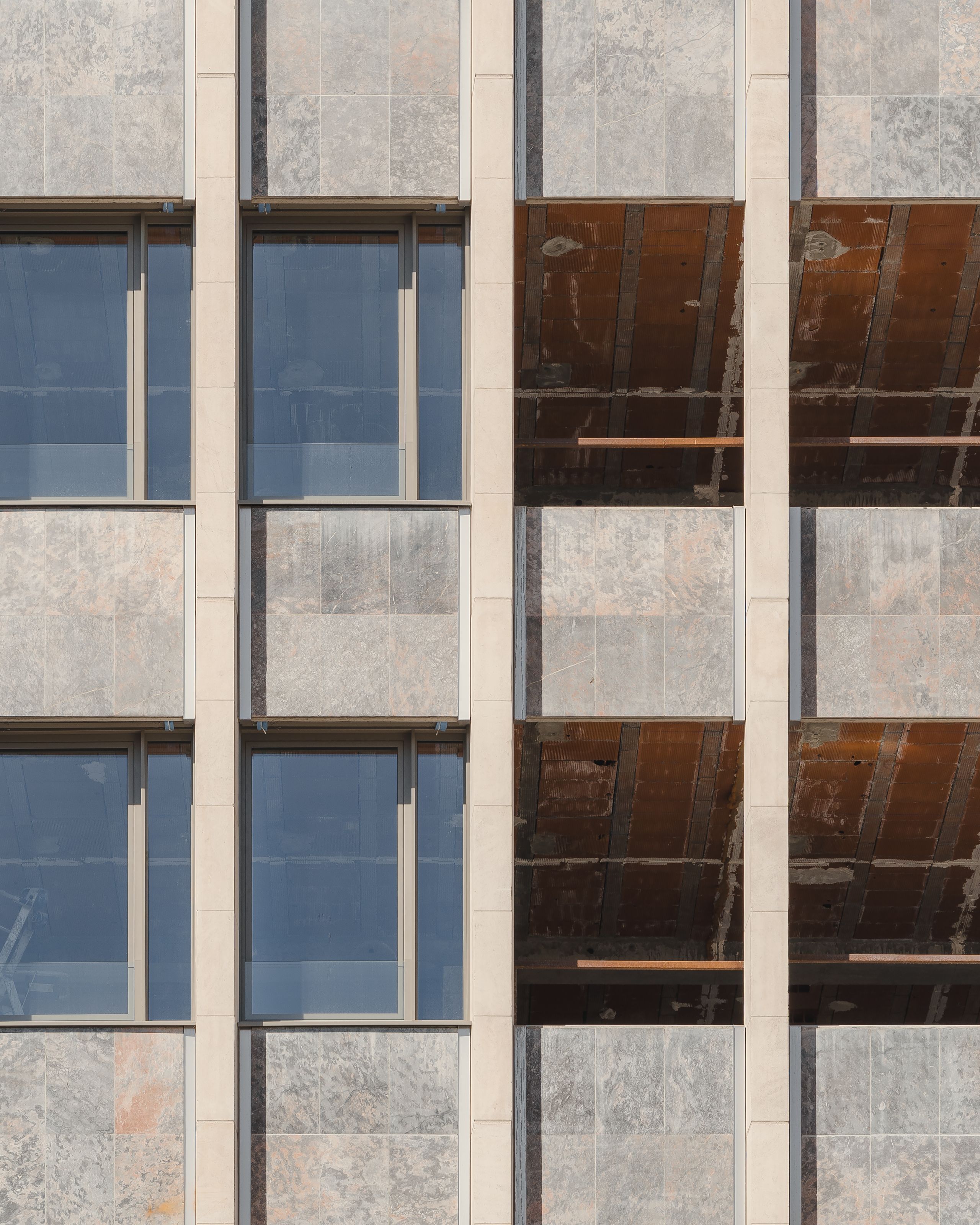 Façade en chantier de l’IGH Émile Loubet à Saint-Étienne, alternant trame de baies vitrées rénovées et travées ouvertes révélant la structure béton.