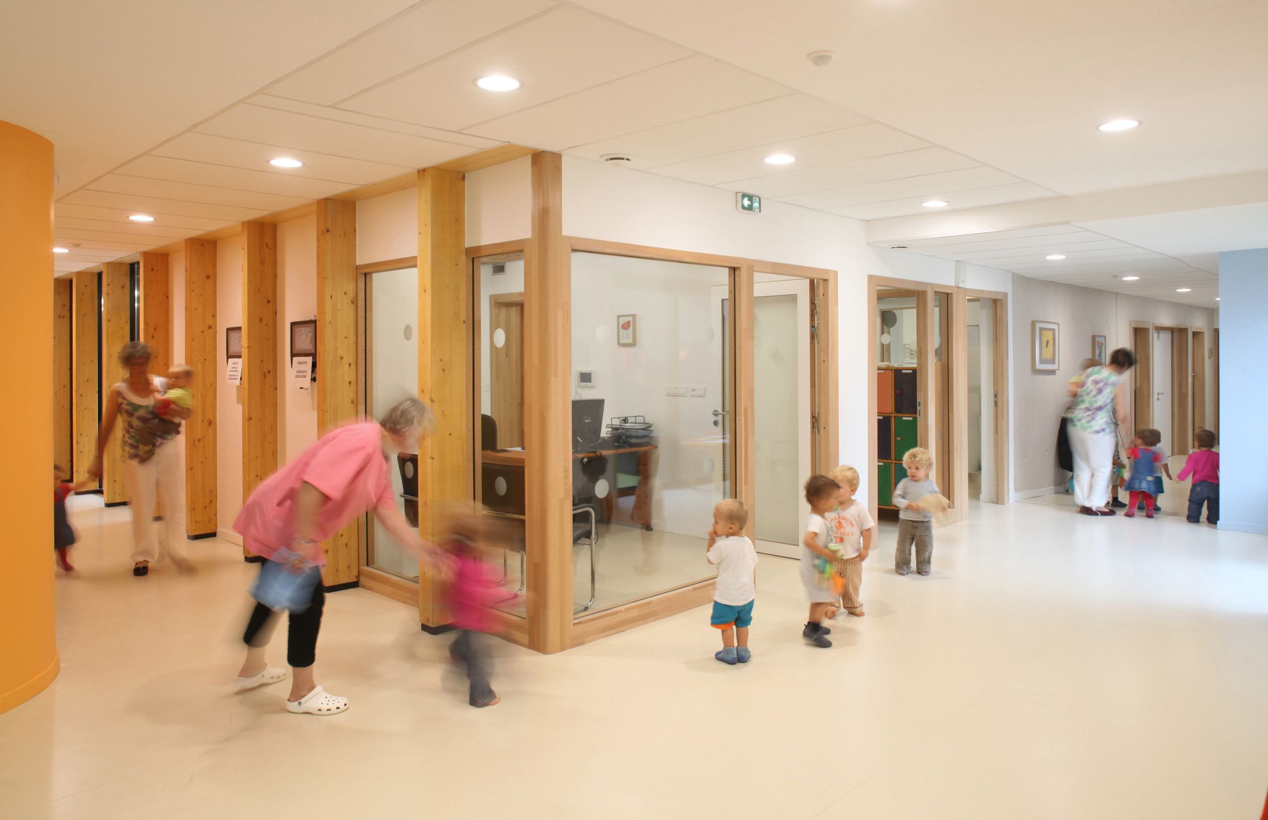 Galerie intérieure lumineuse de la Maison de la petite enfance à Autun, avec bureaux vitrés, structure bois apparente et espace de circulation pour les enfants.