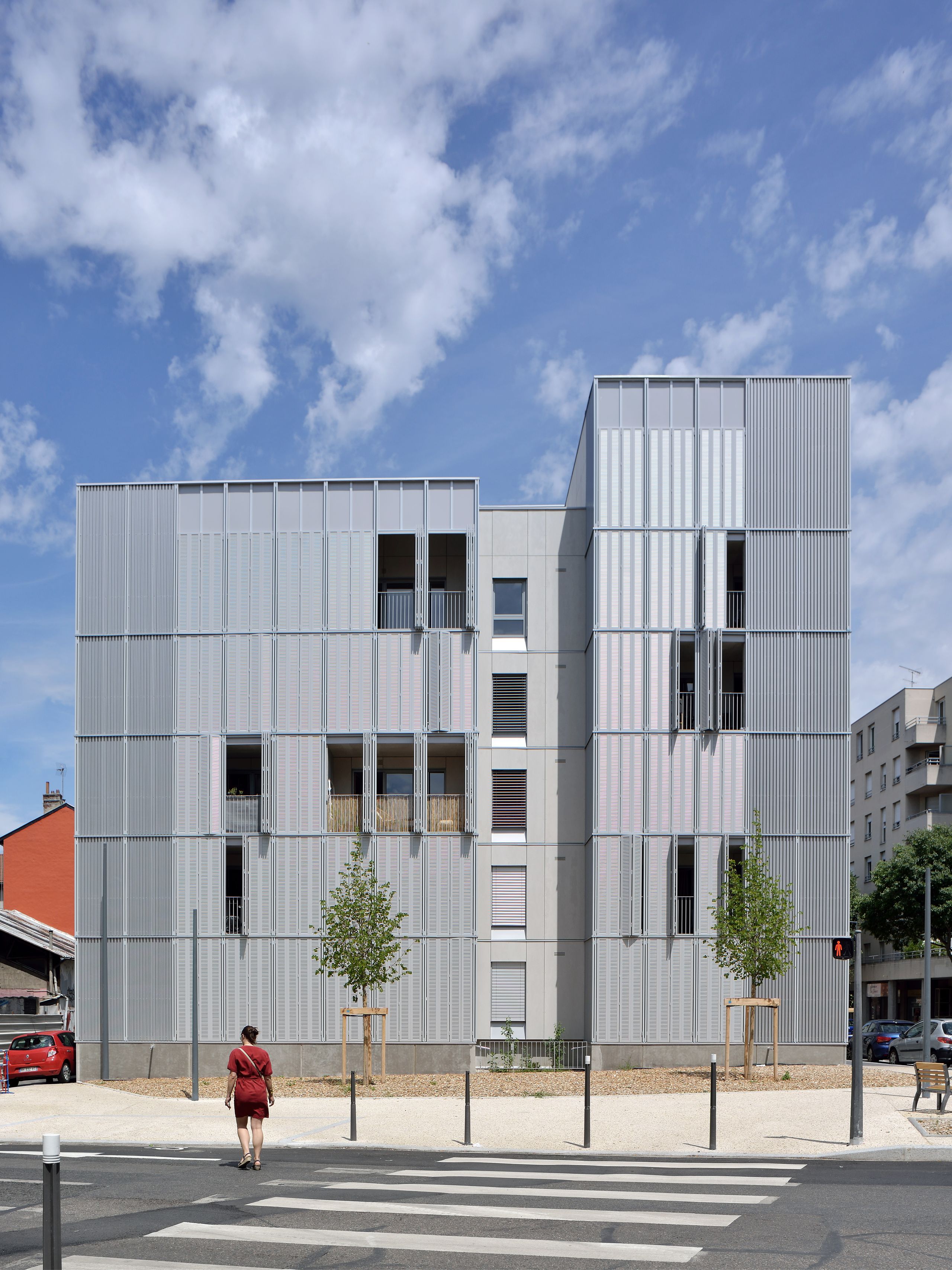 Façade principale des 28 logements Tectoniques à Villeurbanne, volumes décalés en métal perforé, loggias en retrait et circulations extérieures protégées.
