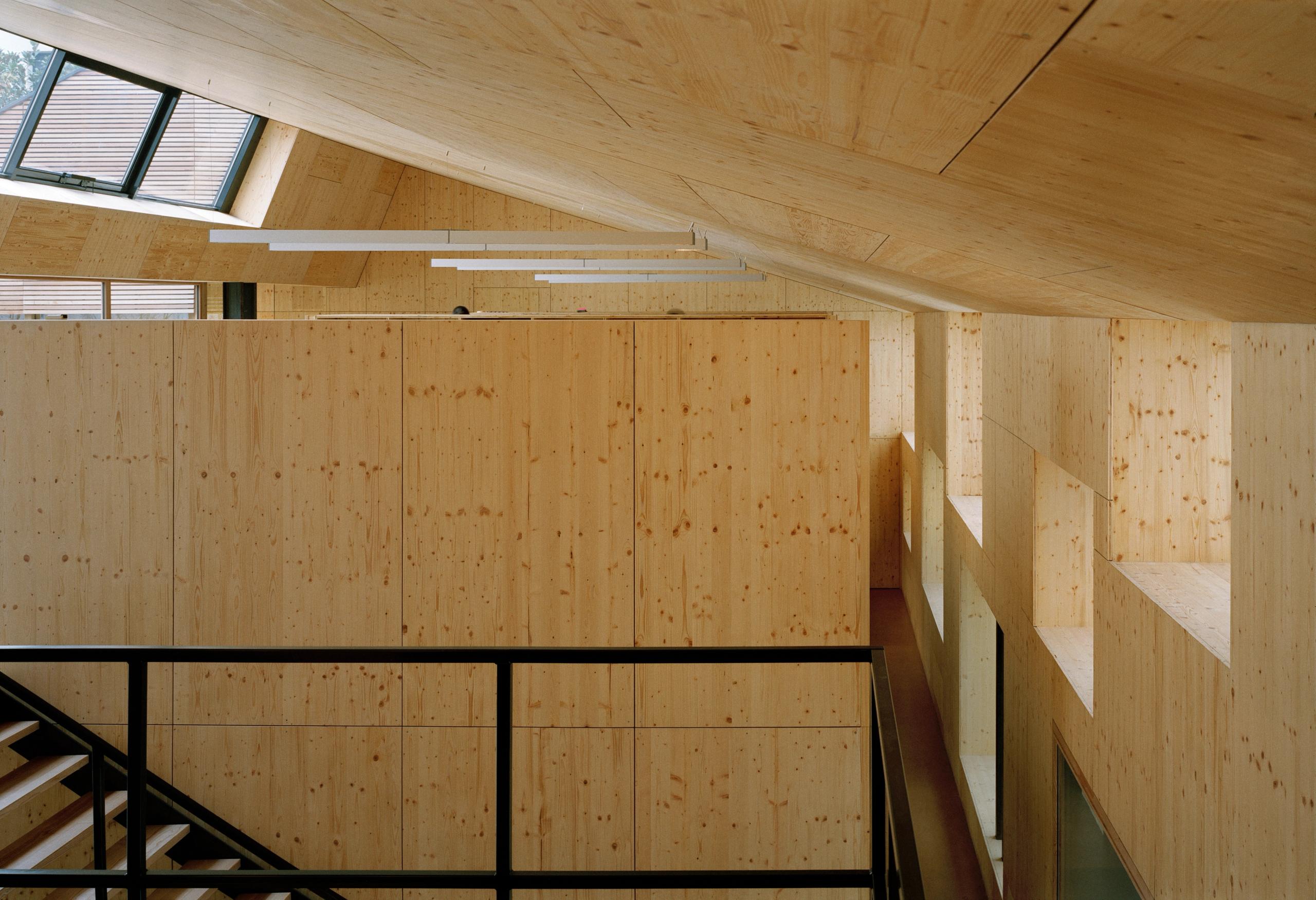 Réhabilitation d’un local d’activité à Lyon par Tectoniques : volume de bureaux en bois lamellé, mezzanine, garde-corps métalliques et lumière zénithale sur patio.
