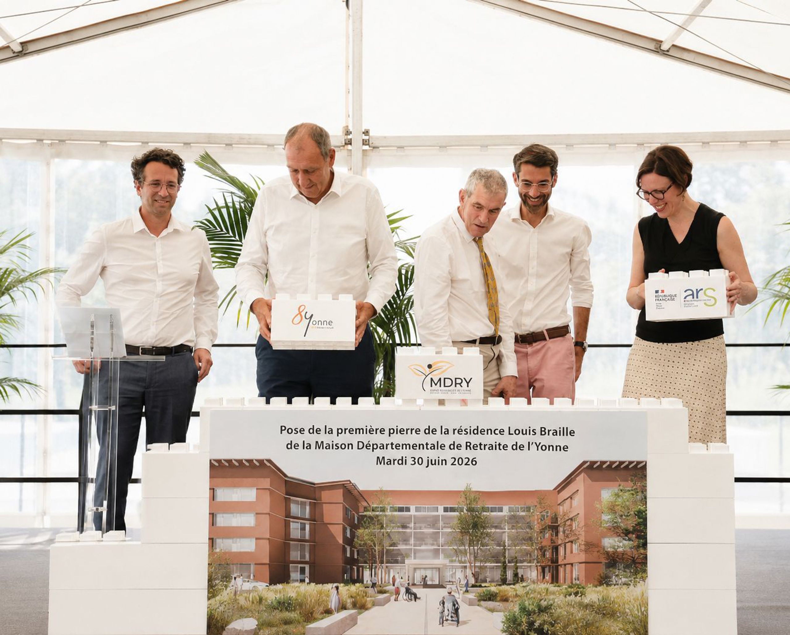 Pose de la première pierre de l’Ehpad Louis-Braille à Auxerre, devant une perspective des pavillons en brique organisés autour d’un jardin.