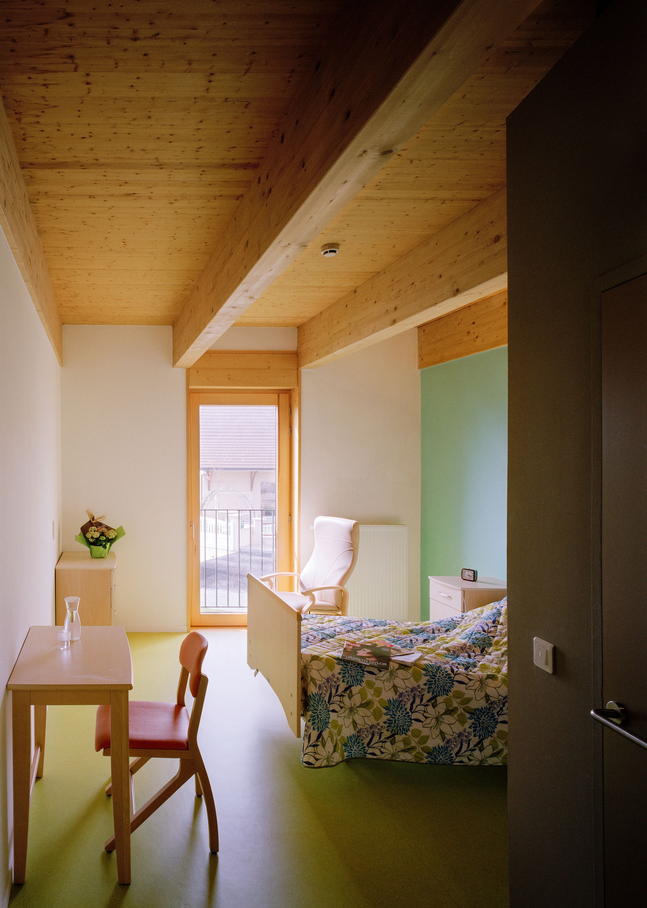 Chambre de l’EHPAD de Mervans par Tectoniques, avec structure bois apparente, grande baie vitrée sur le jardin et aménagement sobre de type domestique.