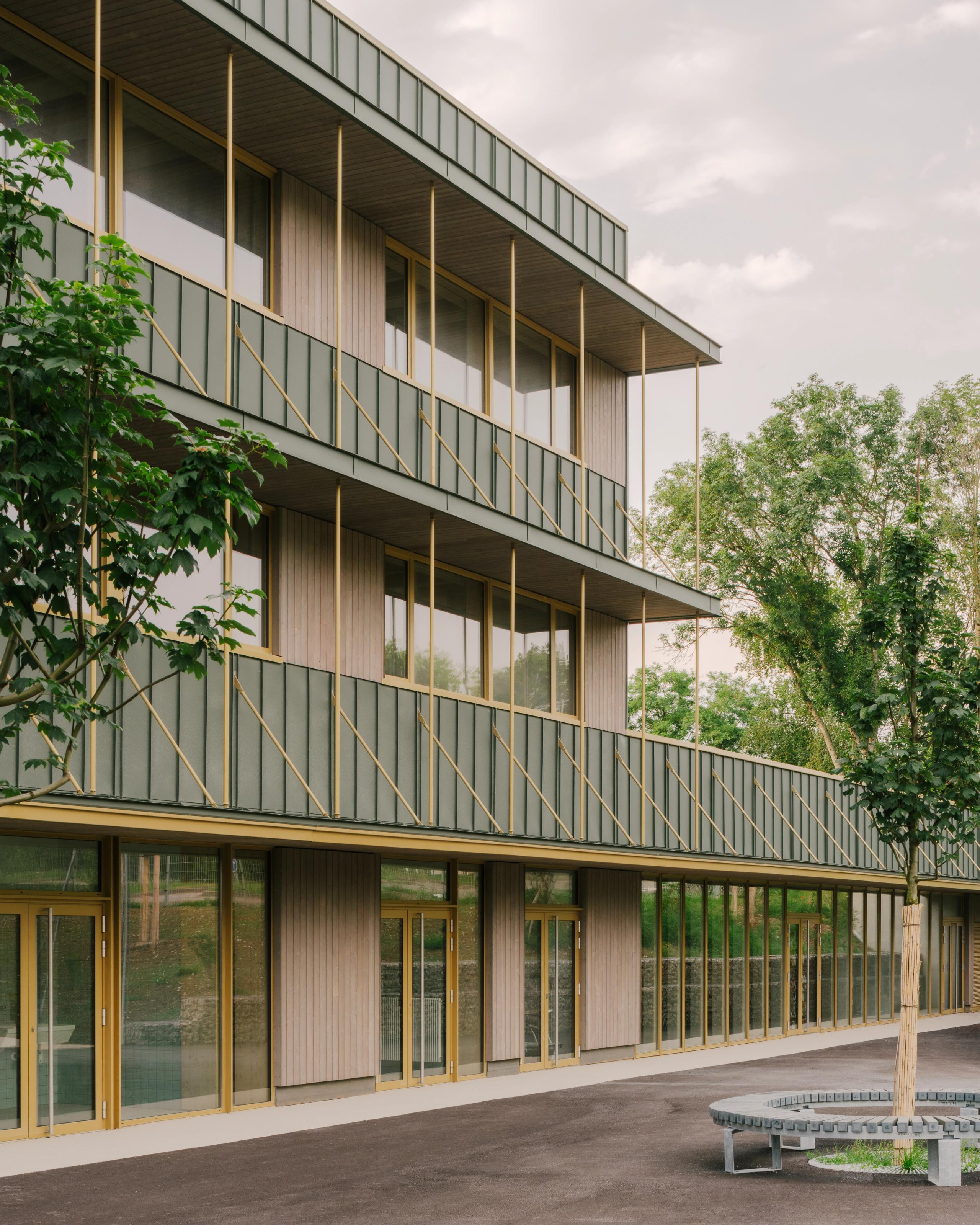 Façade restructurée du collège Maryse Bastié à Dole : extension bois-béton à trois niveaux, grands vitrages, bardage vertical et garde-corps métalliques rythmés.