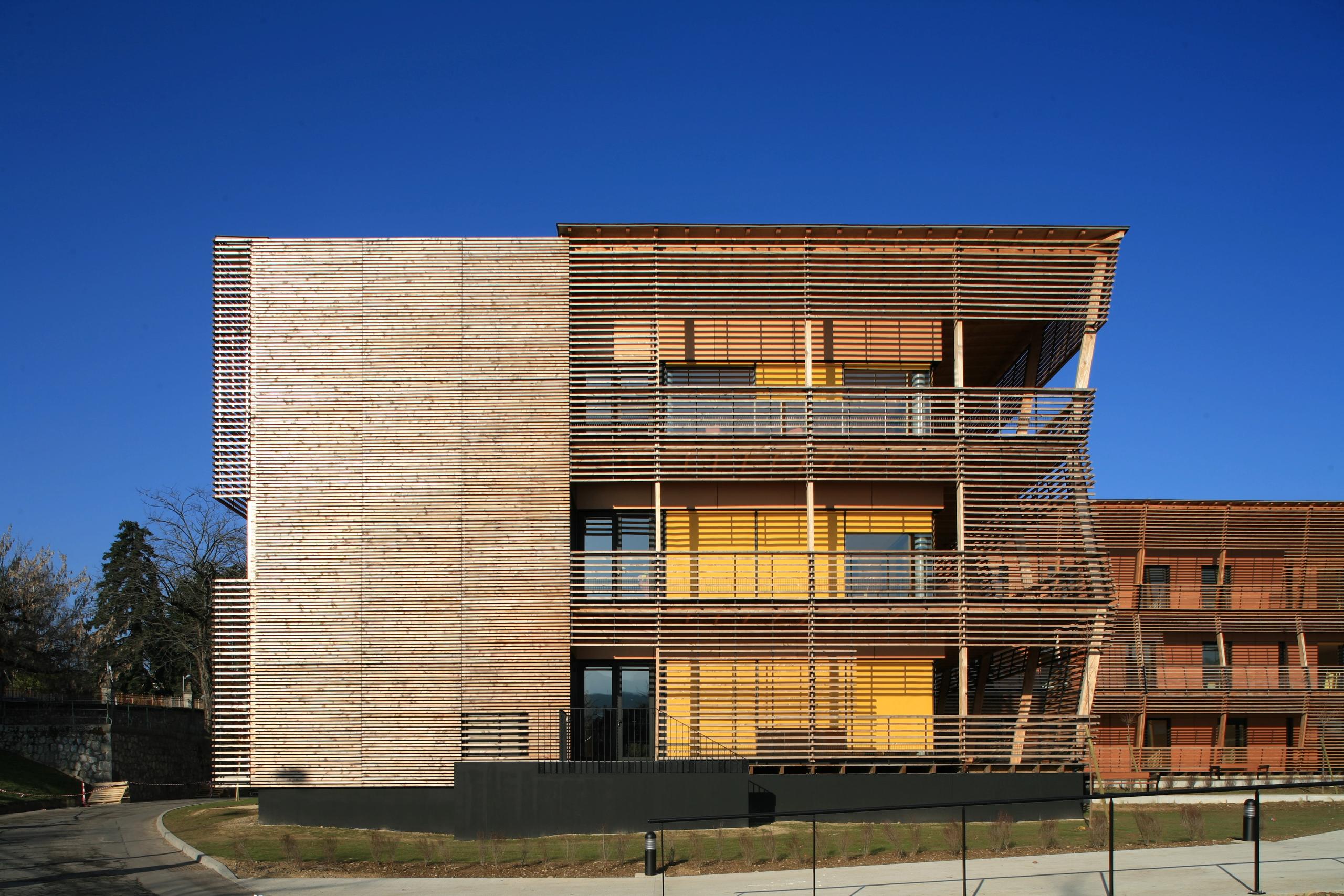 Façade de l’EHPAD de Chambéry par Tectoniques, volume en T à structure béton et parement de tasseaux bois, grandes terrasses filantes ouvertes sur le paysage.