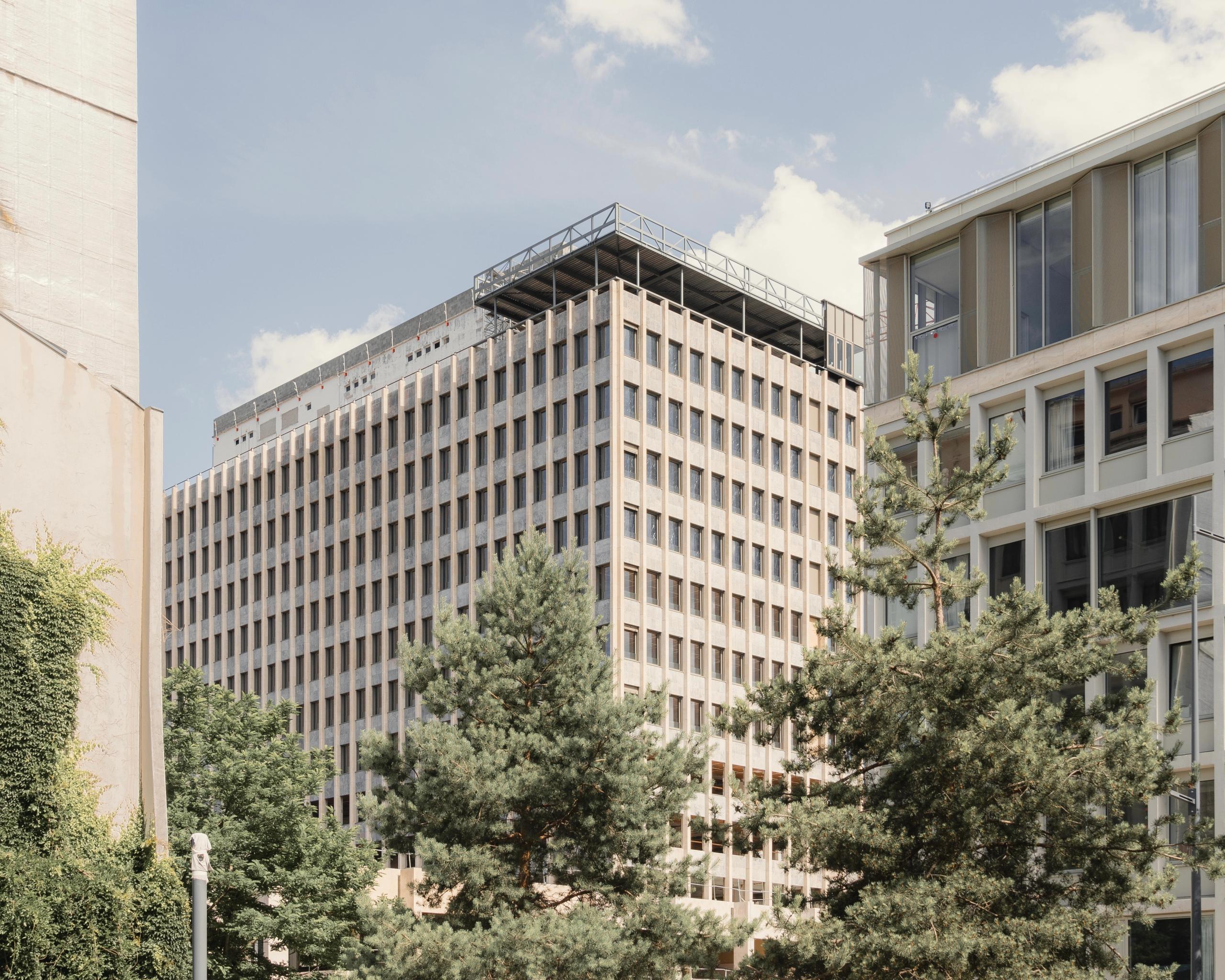 Vue de l’ancien IGH Émile Loubet à Saint-Étienne en cours de réhabilitation, tour administrative des années 1970 à trame béton régulière, surmontée d’un nouveau volume technique.