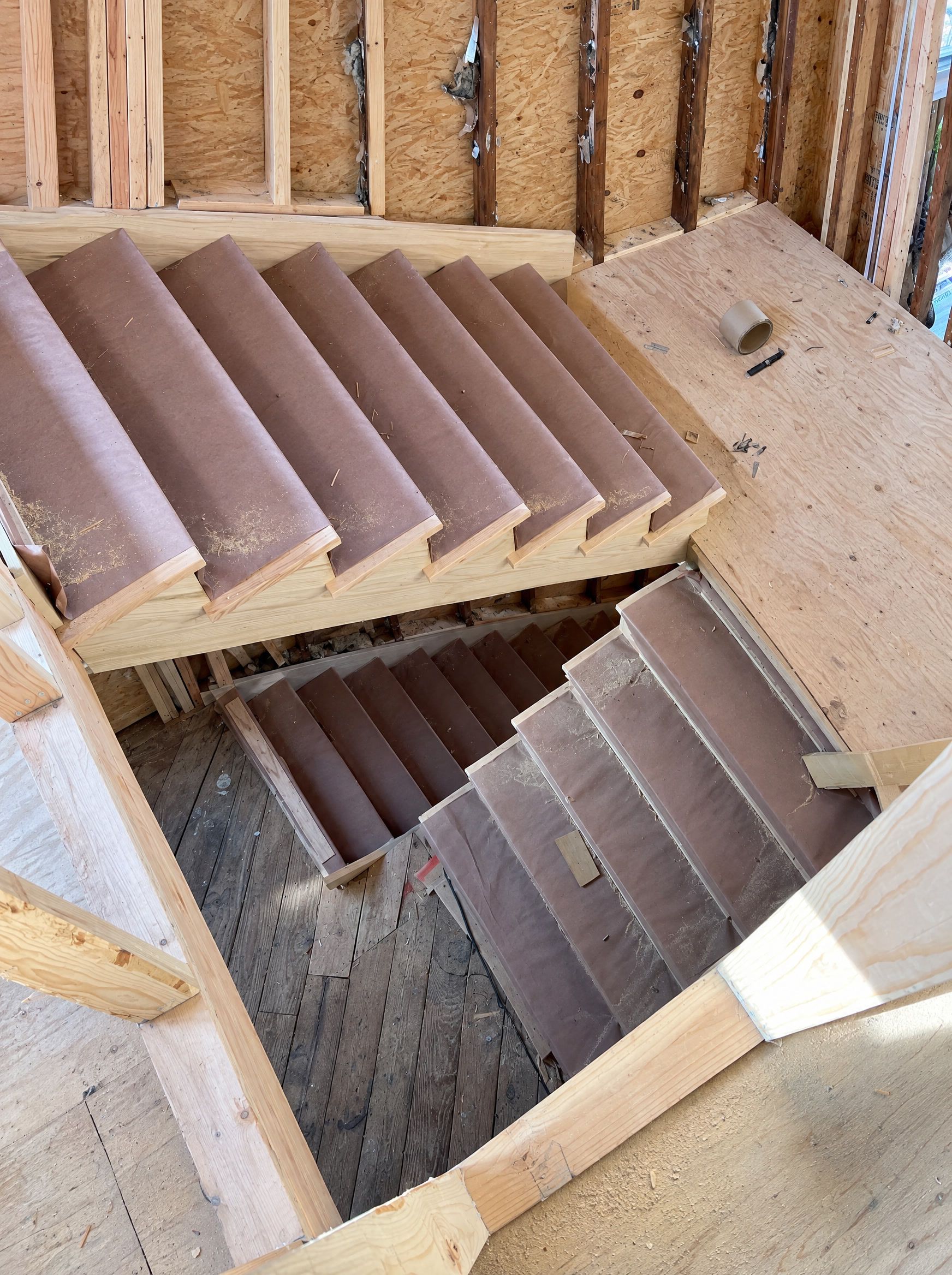 The new staircase from above, treads under protective paper, the old floor below