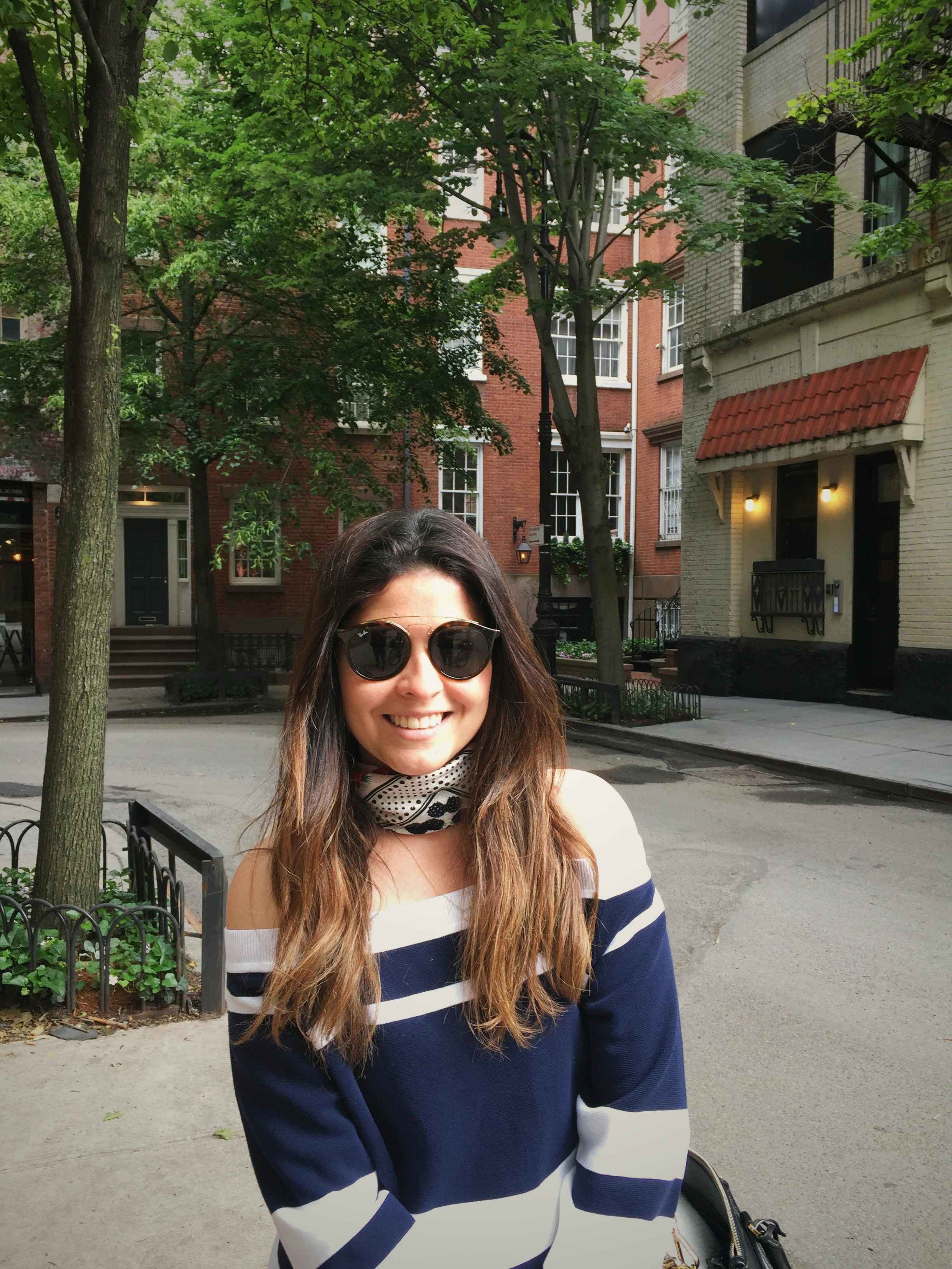 Cacau Martins, founder of SOU Design Studio, smiling on a tree-lined street