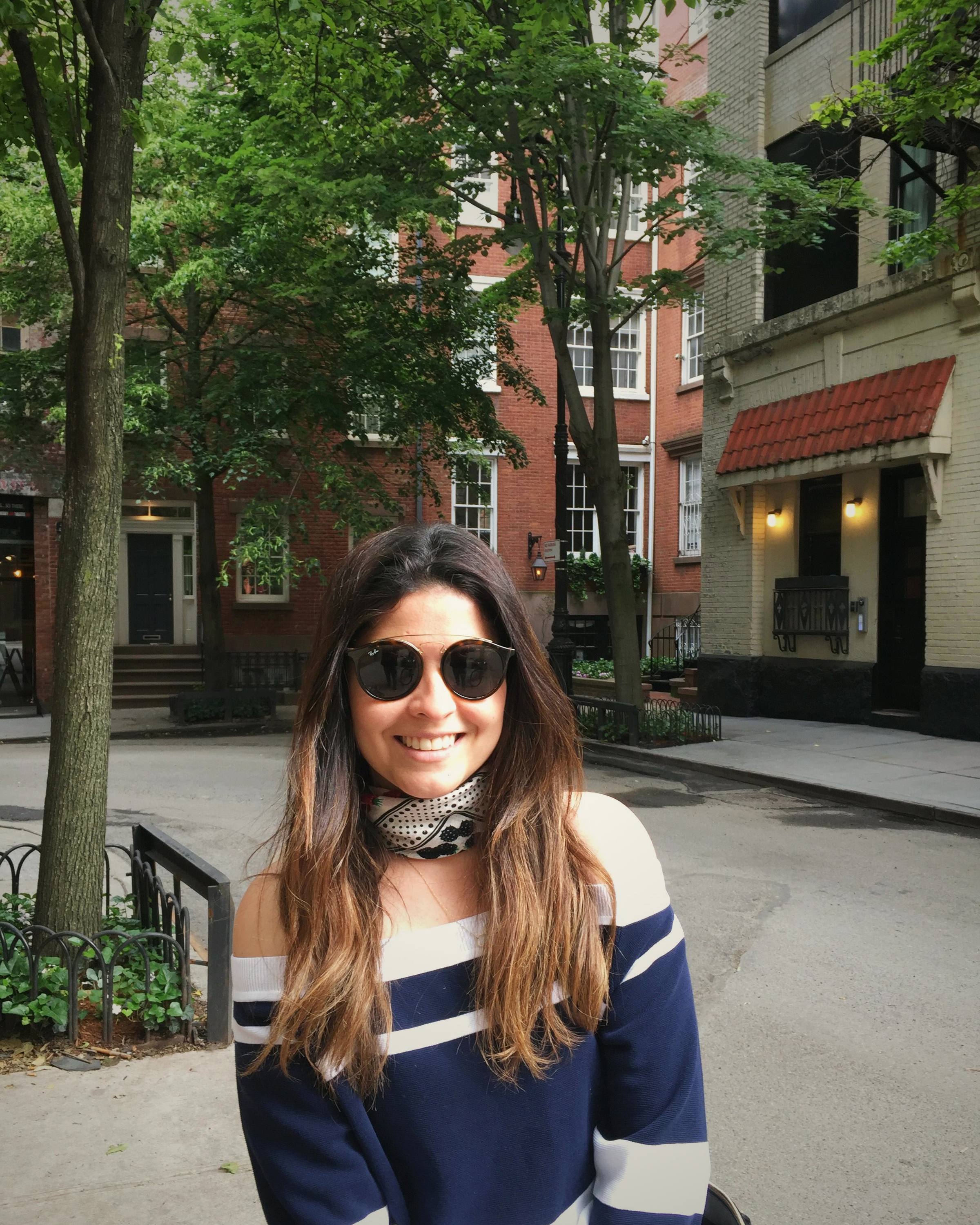 Cacau Martins, founder of SOU Design Studio, smiling on a tree-lined street