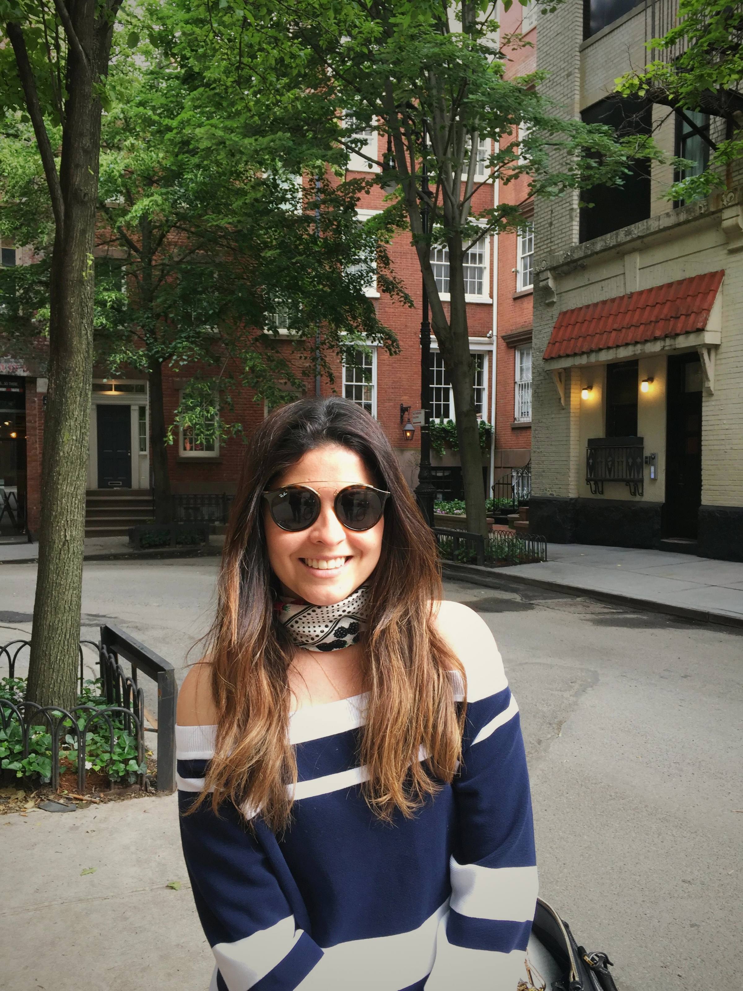 Cacau Martins, founder of SOU Design Studio, smiling on a tree-lined street