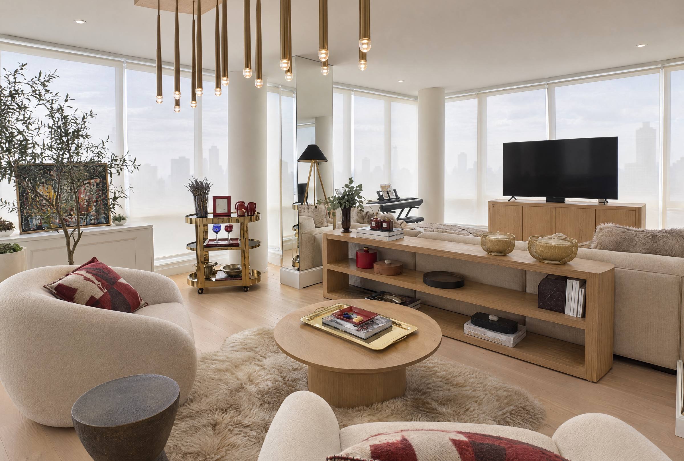 Living room seating area with a cluster of brass pendant lights, cream boucle armchairs and a sheepskin rug, Upper East Side apartment