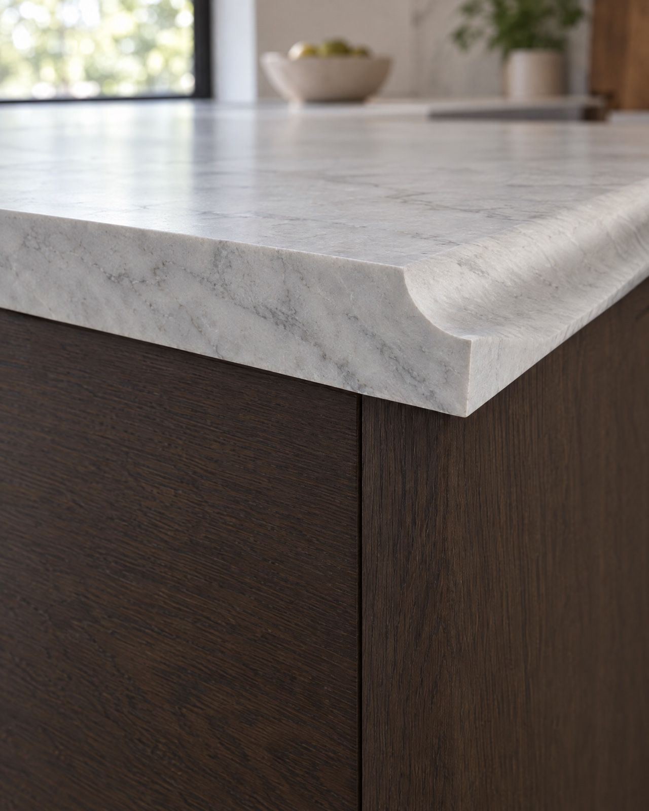 The cut end of a pale grey marble countertop showing a cove edge in section: a concave scoop out of the top corner