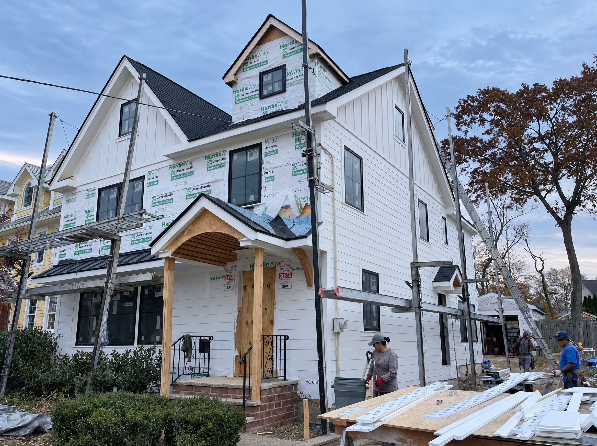 The front corner at dusk, siding nearly complete, the dormer still wrapped