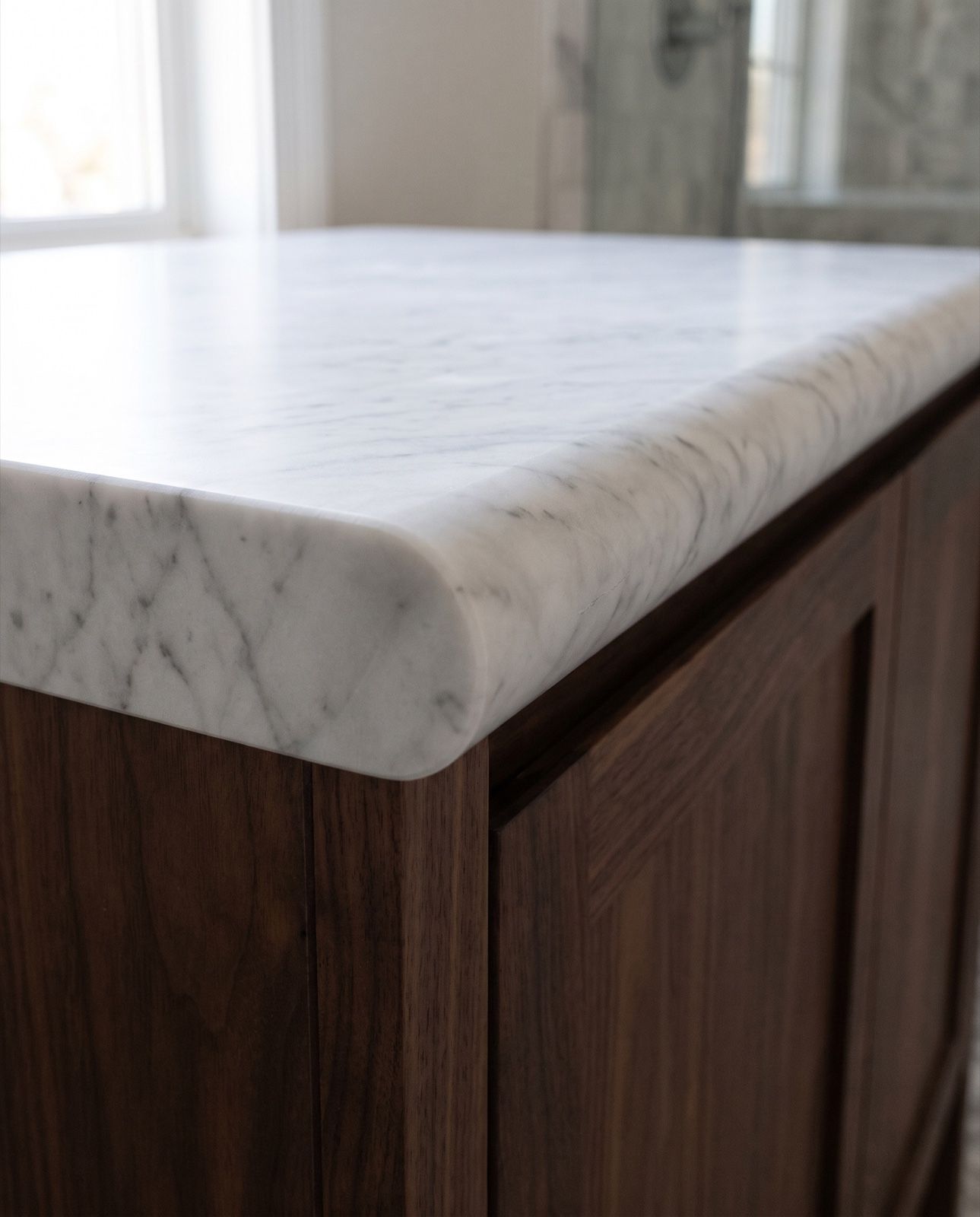 The cut end of a white marble vanity top showing a full bullnose edge in section: a half circle