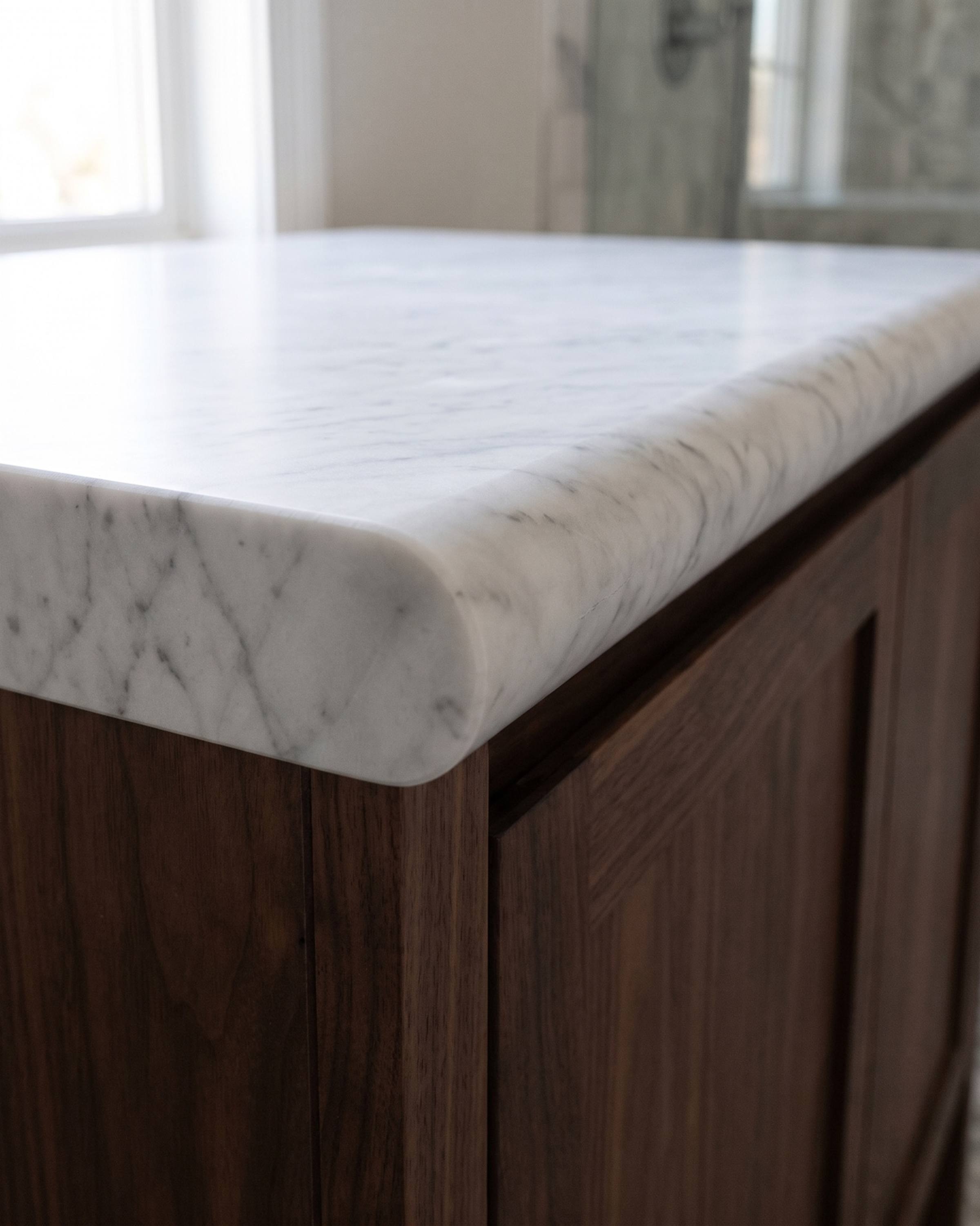 The cut end of a white marble vanity top showing a full bullnose edge in section: a half circle