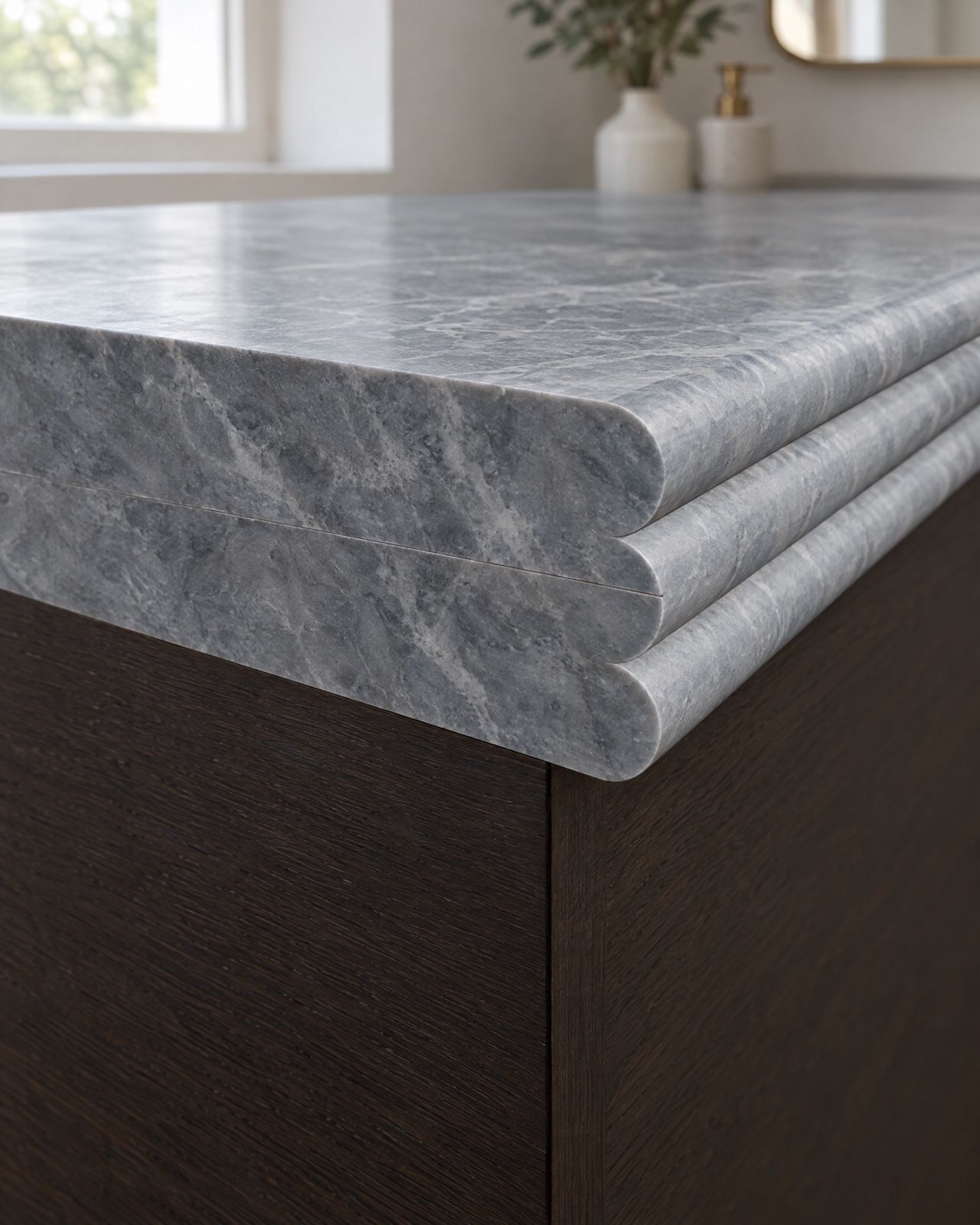 The cut end of a blue-grey marble vanity top showing a triple bullnose in section: three stacked rounded layers