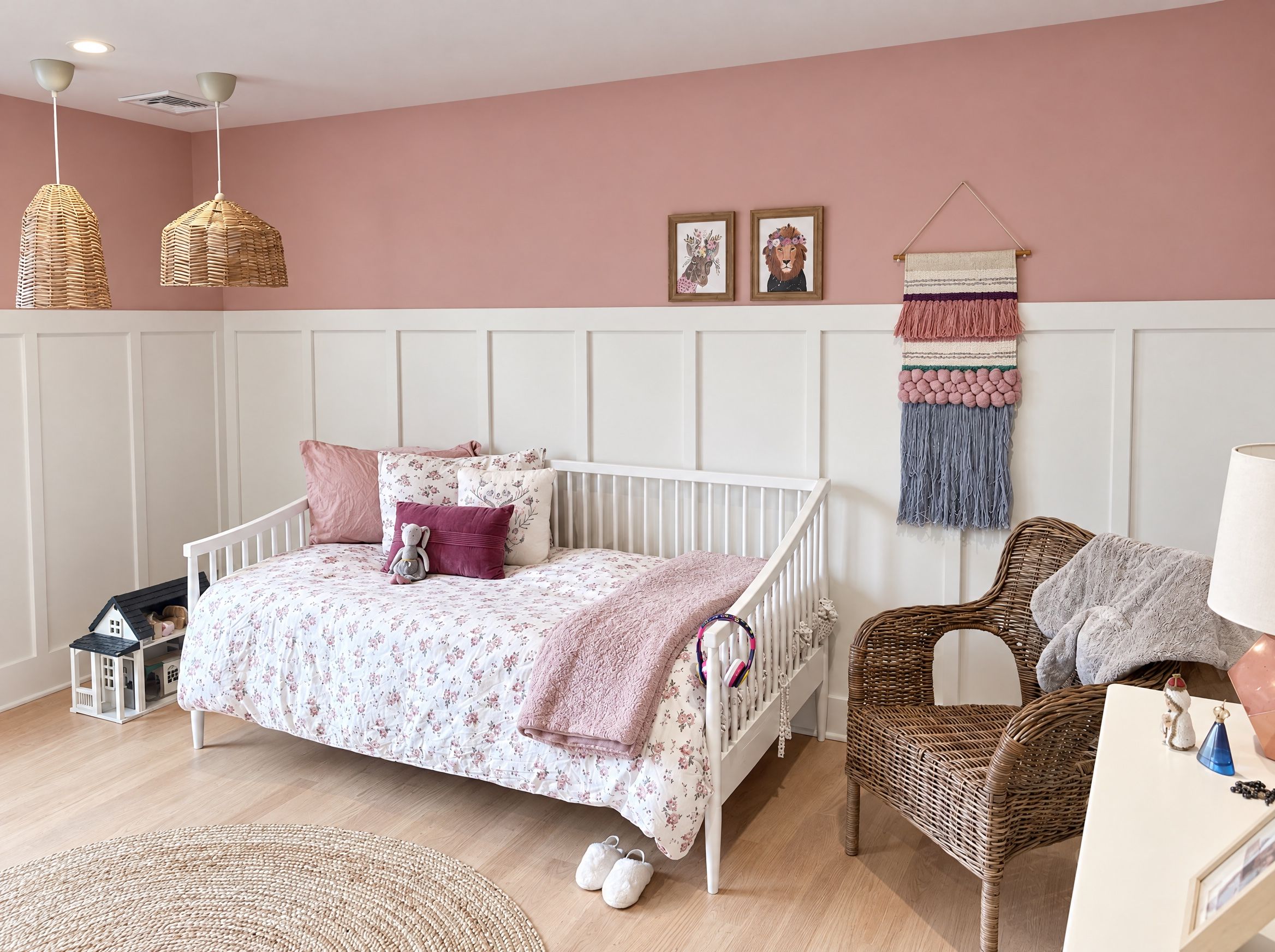 A white spindle daybed with a floral duvet under two rattan pendants in the girls' bedroom