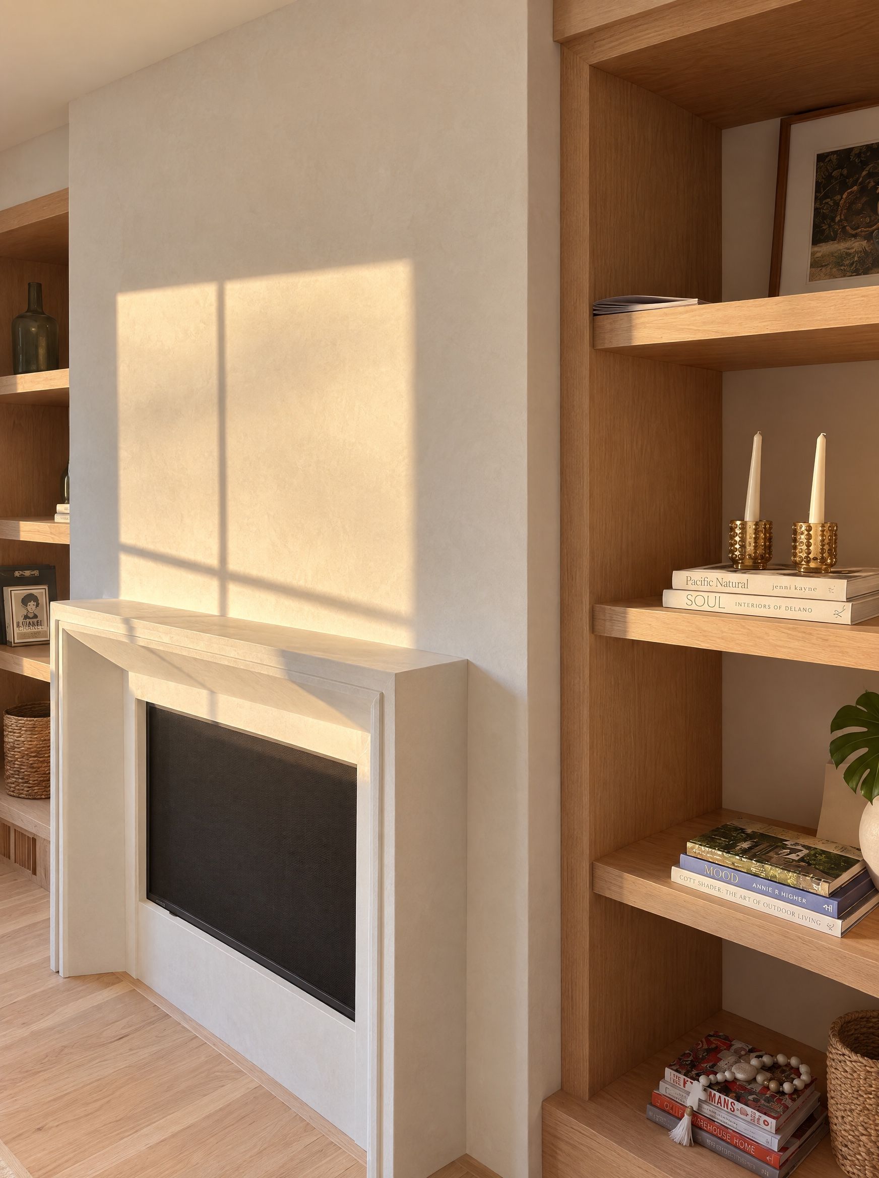Late sun on the plaster fireplace wall beside the oak bookcase