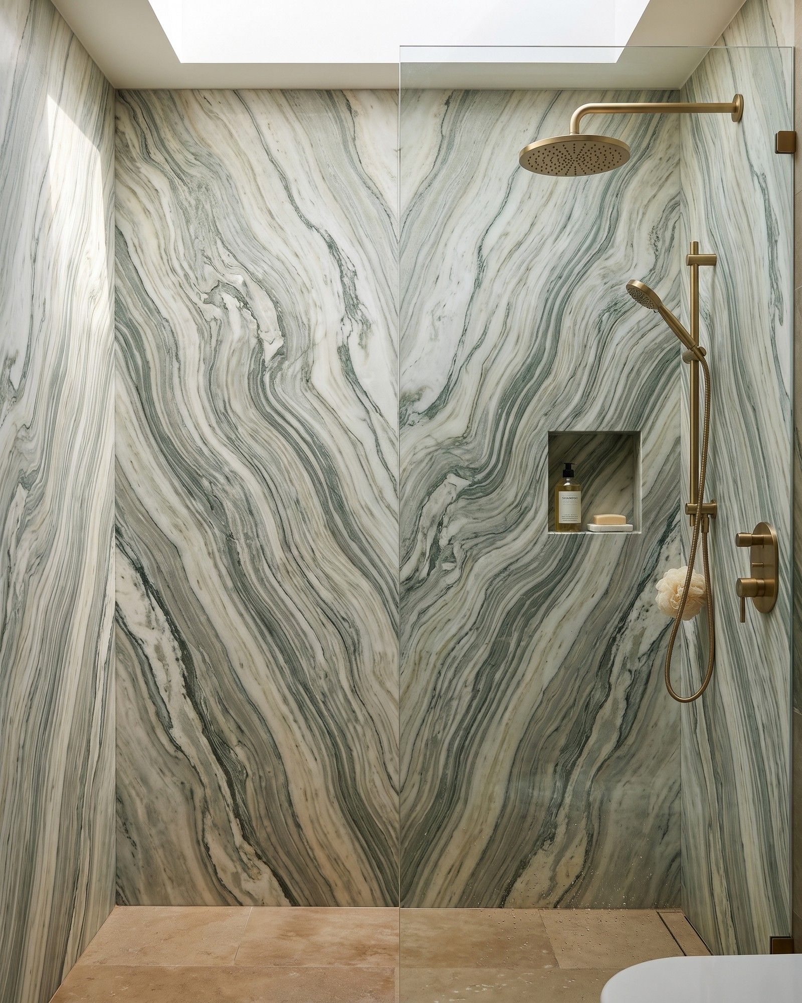 A walk-in shower with bookmatched honed Cipollino marble walls, rippling green-grey and cream bands running vertically
